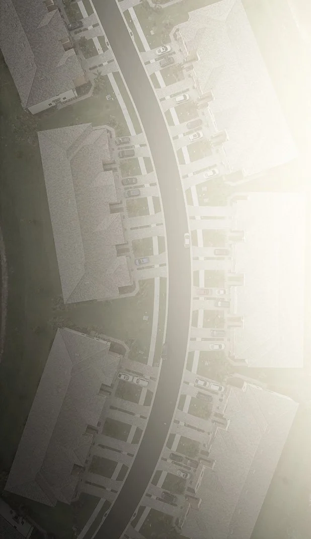 An aerial view of a residential neighborhood with houses, driveways, cars parked; a curved street runs through the area.