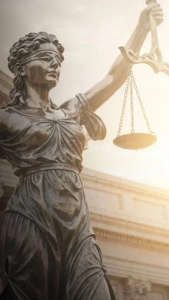 Close-up of the statue of Lady Justice holding scales, with a building in the background.