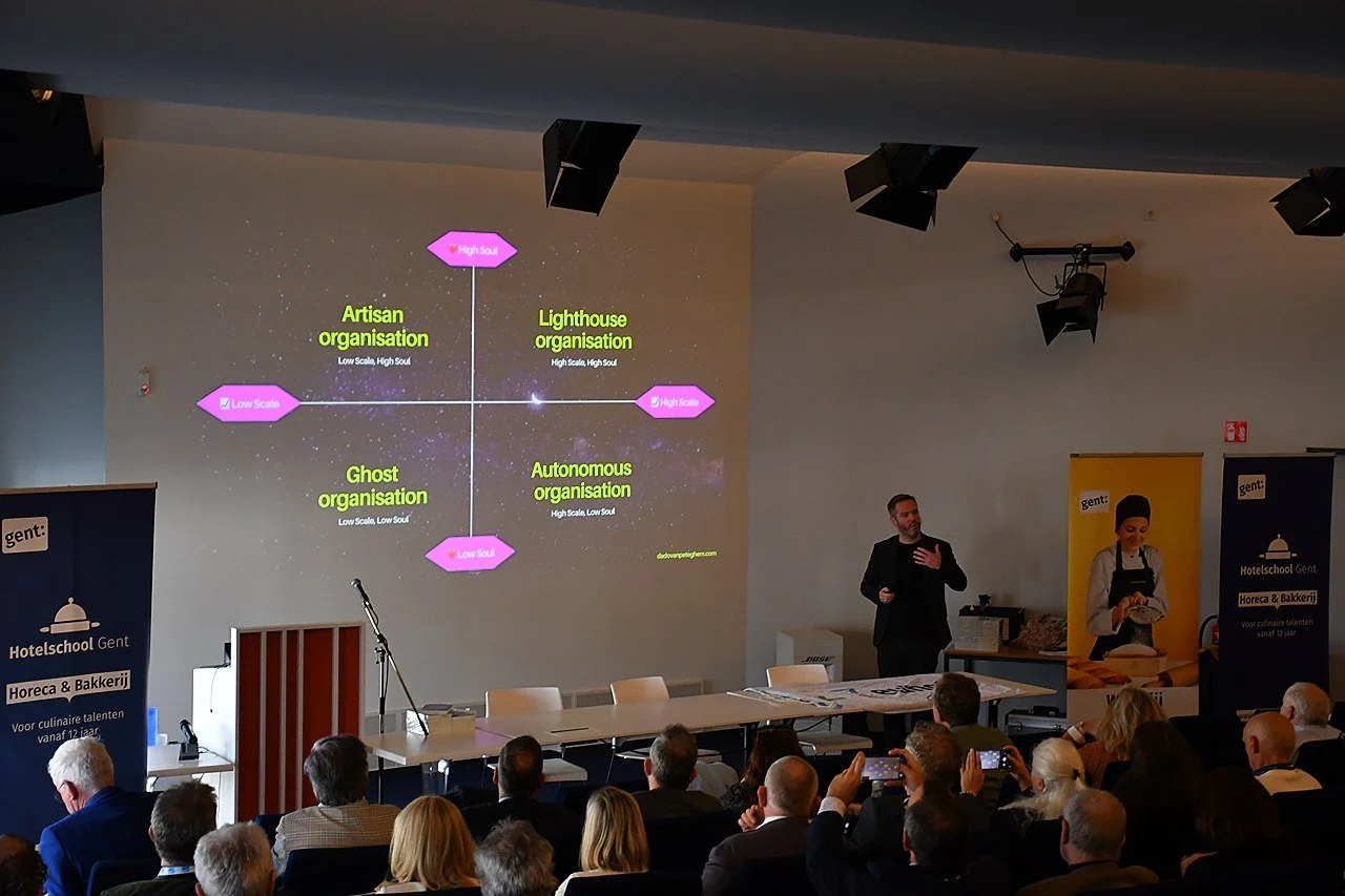 One of the speakers presenting a diagram on a large screen showing four types of organizations: Artisan, Lighthouse, Ghost, and Autonomous, with labels indicating low or high scale and high or low soul, at EUHOFA Congress session.