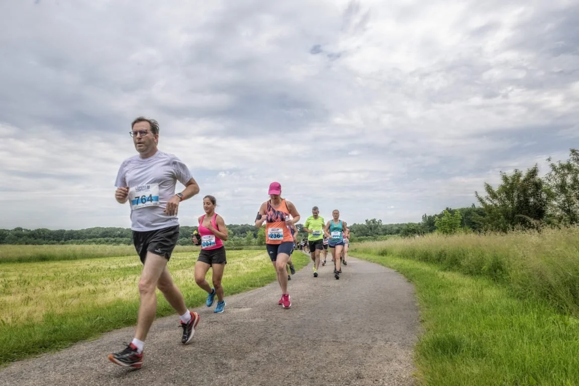 Runners on a scenic route surrounded by green countryside.