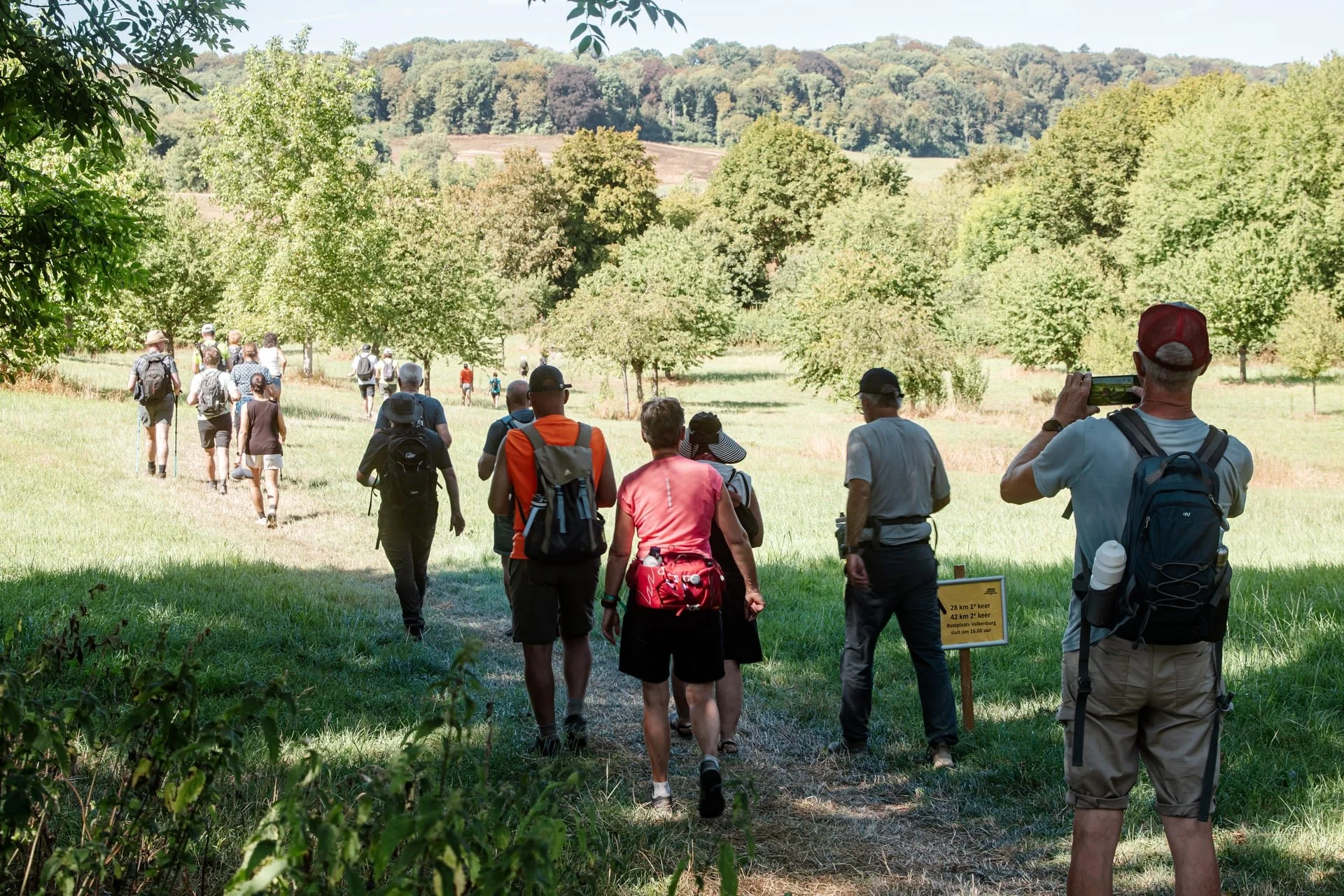 Hikers in a hilly landscape. One hiker makes a picture of fellow hikers in the beautiful green hillside landscape