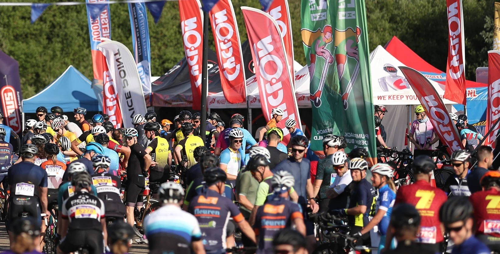 Event village with start and finish line, food stands, cycling services, and entertainment.