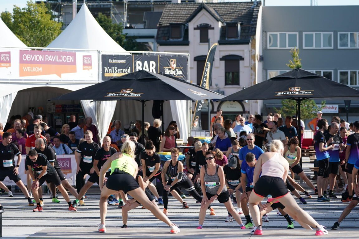 Group of runners taking part in a guided warm-up session before the start.