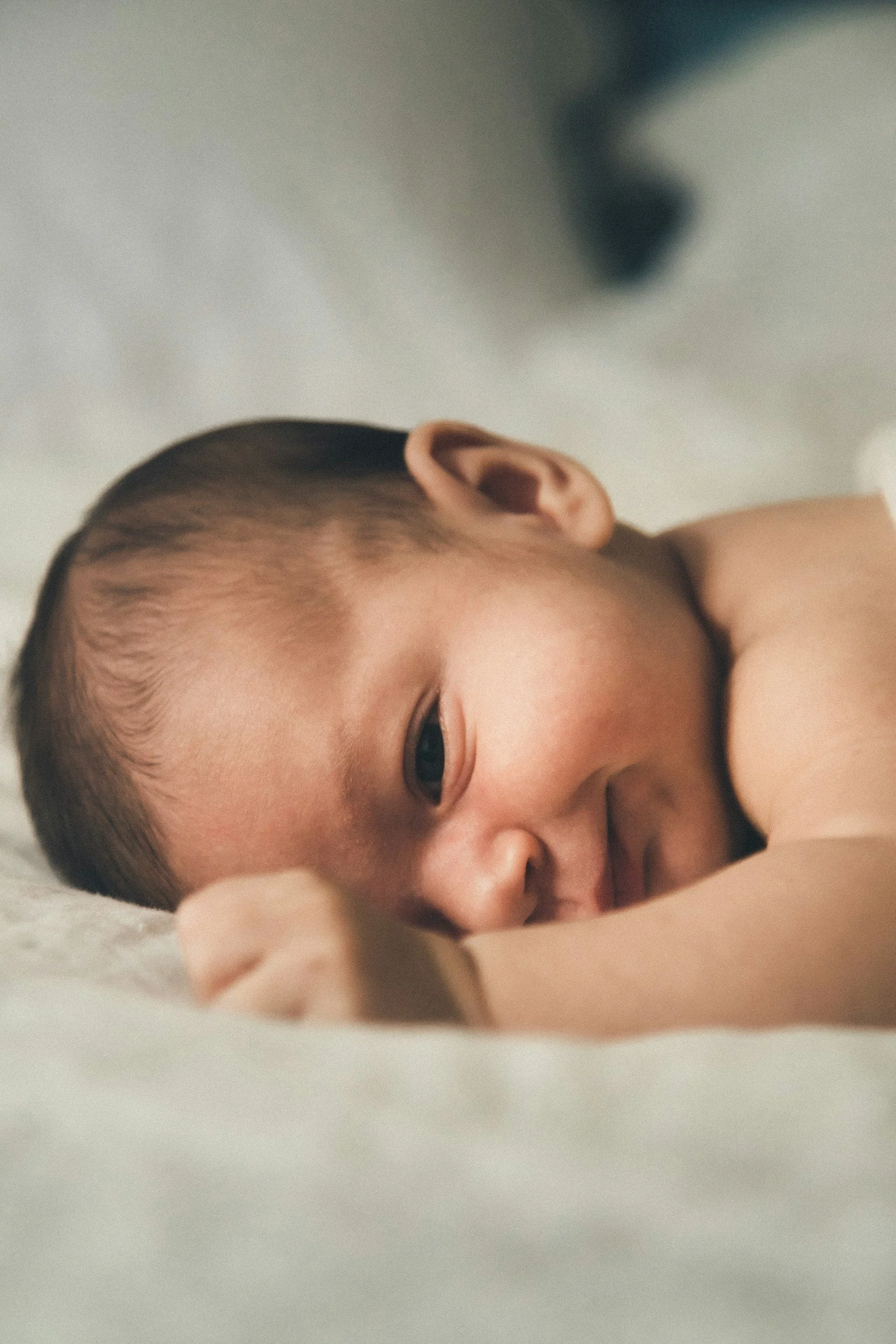 Close-up of a sleeping baby with a peaceful expression, lying on a soft surface.