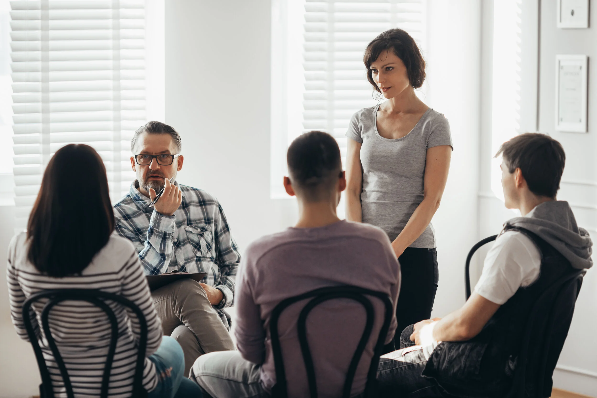 woman-stands-in-front-of-a-group-of-people-during--A4CA2BK.jpg