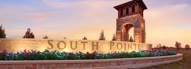 South Pointe sign with a stone tower and landscaped flowers at sunset