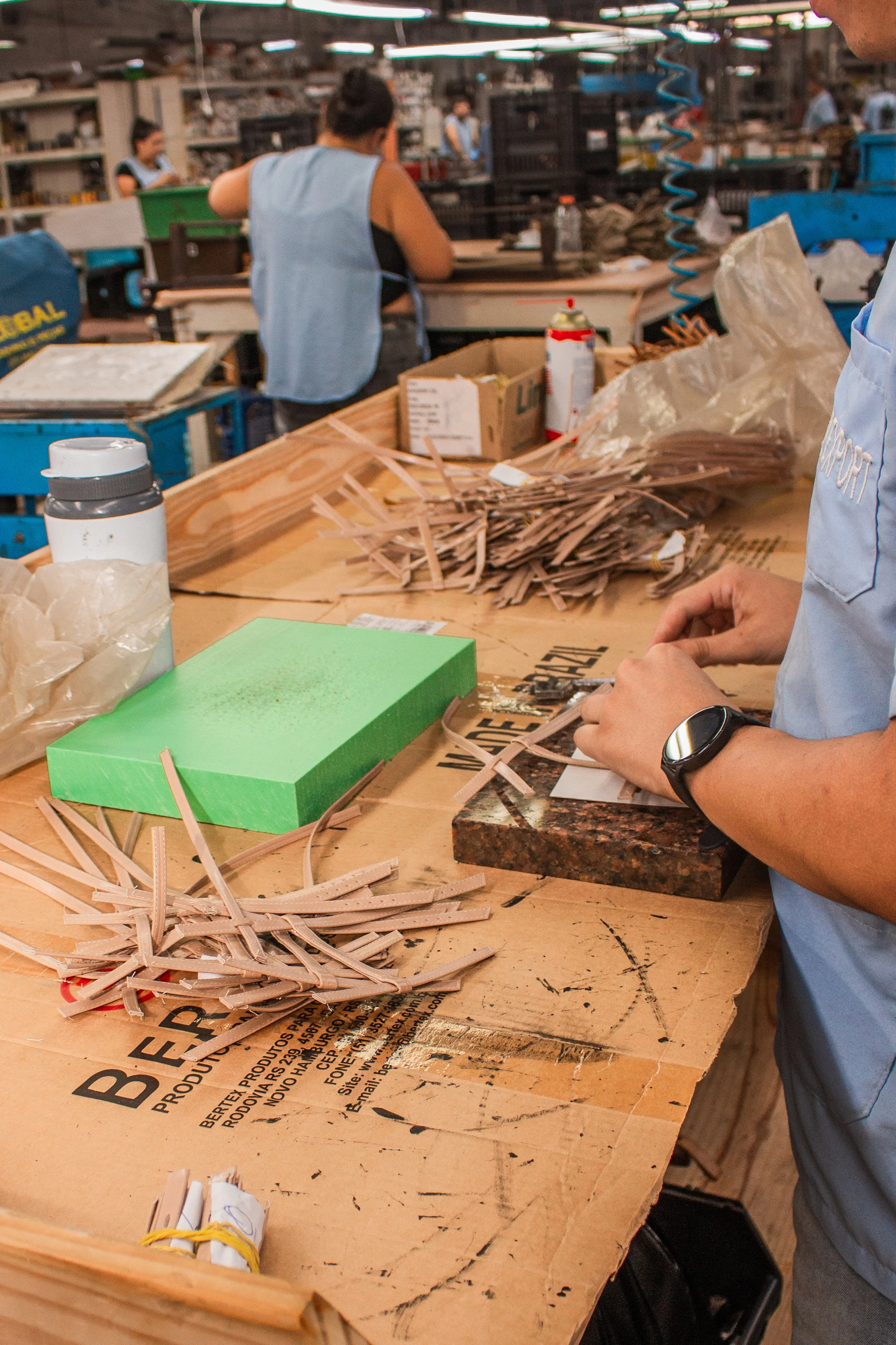 Imagem de uma fábrica de packaging artesanal, com pessoas trabalhando em colagem de materiais de papel.