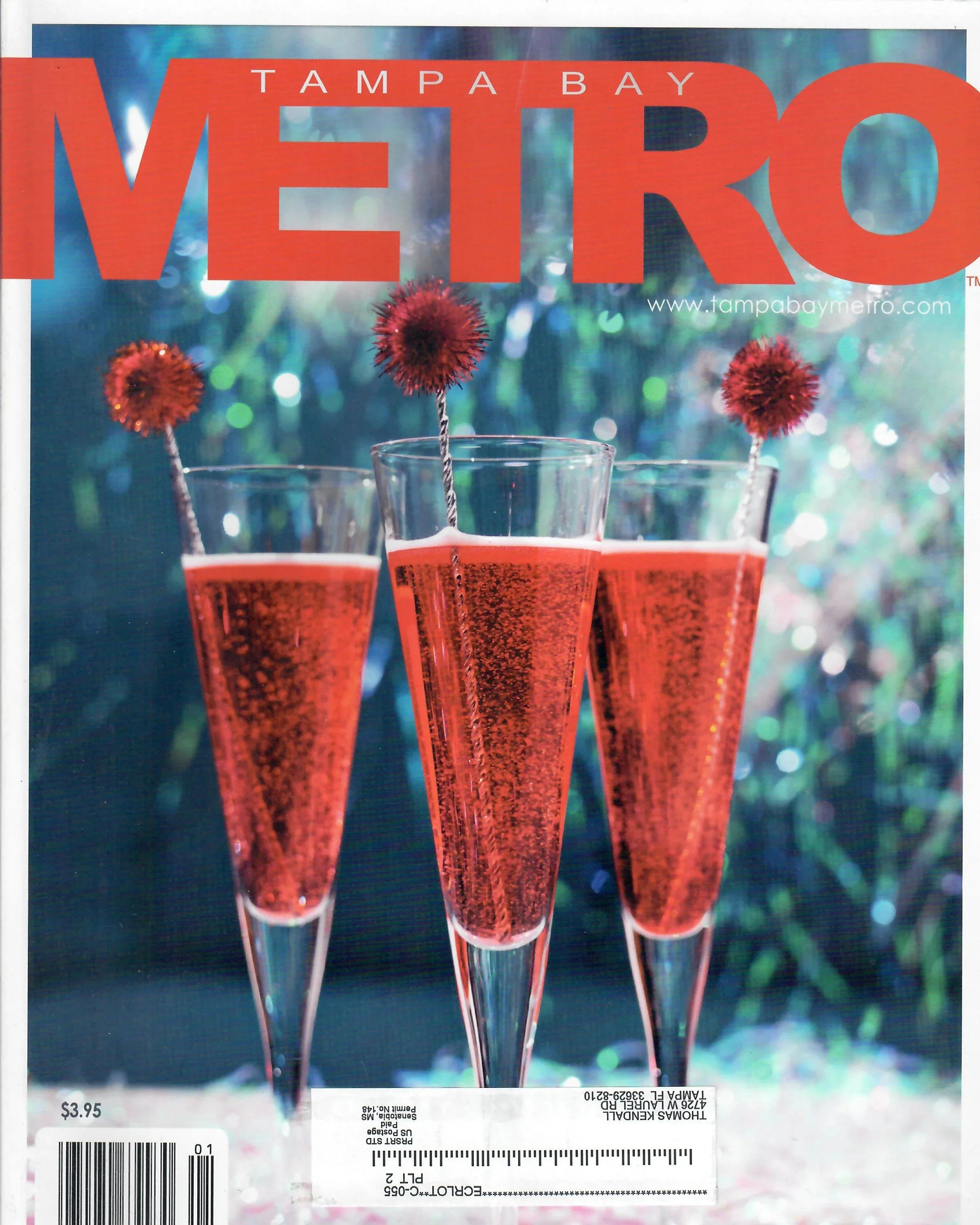A Tampa Bay Metro newspaper advertisements featuring three red glasses with cocktail stirrers topped with red fluffy pom-pom decorations, set against a blurred, colorful bokeh background. The price of $3.95 and a barcode are visible at the bottom.