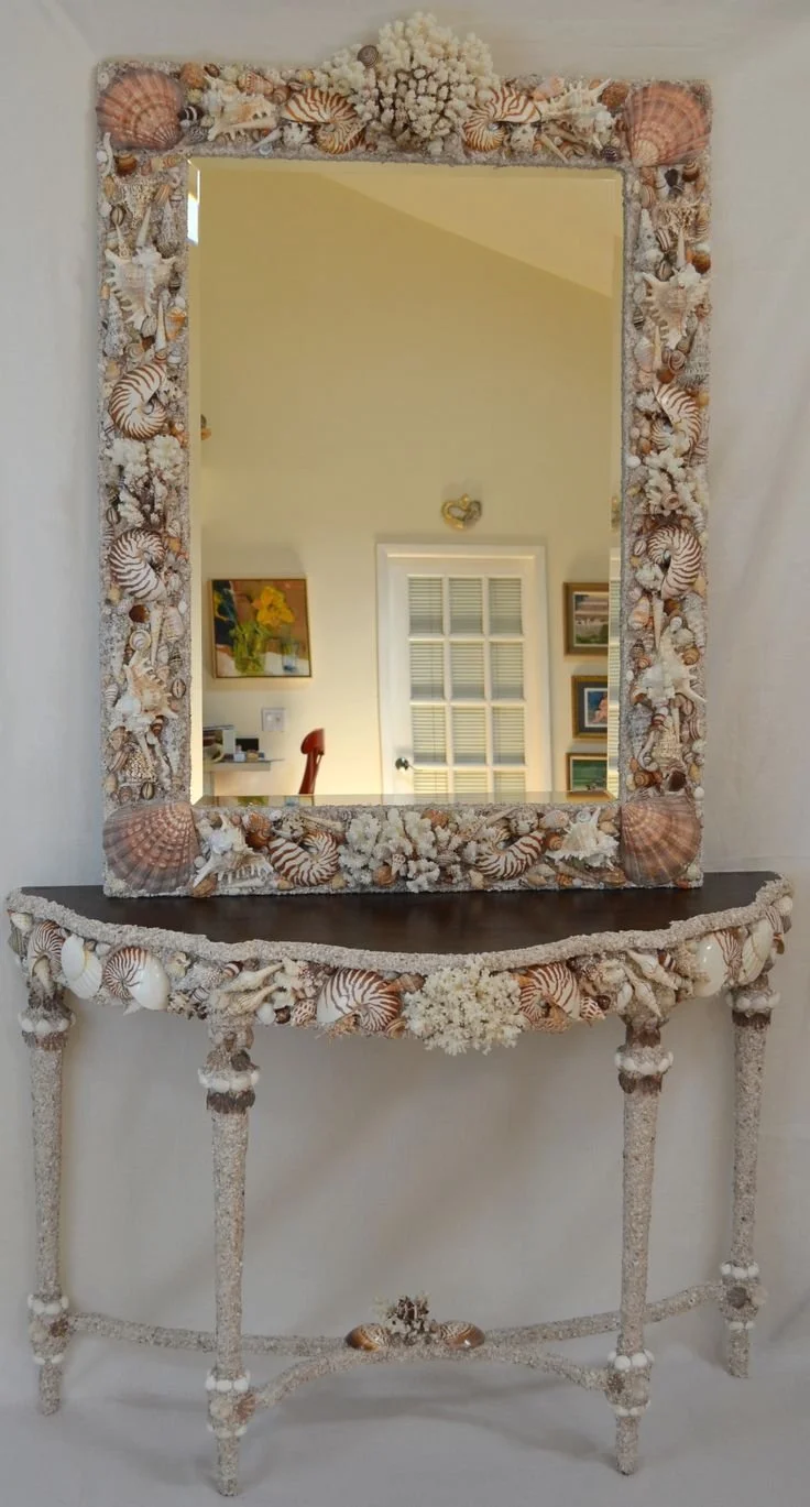 A seashell mirror atop a seashell console.  