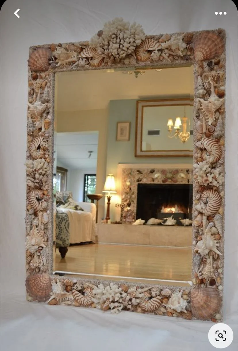 Coastal seashell mirror reflecting a custom seashell fireplace.