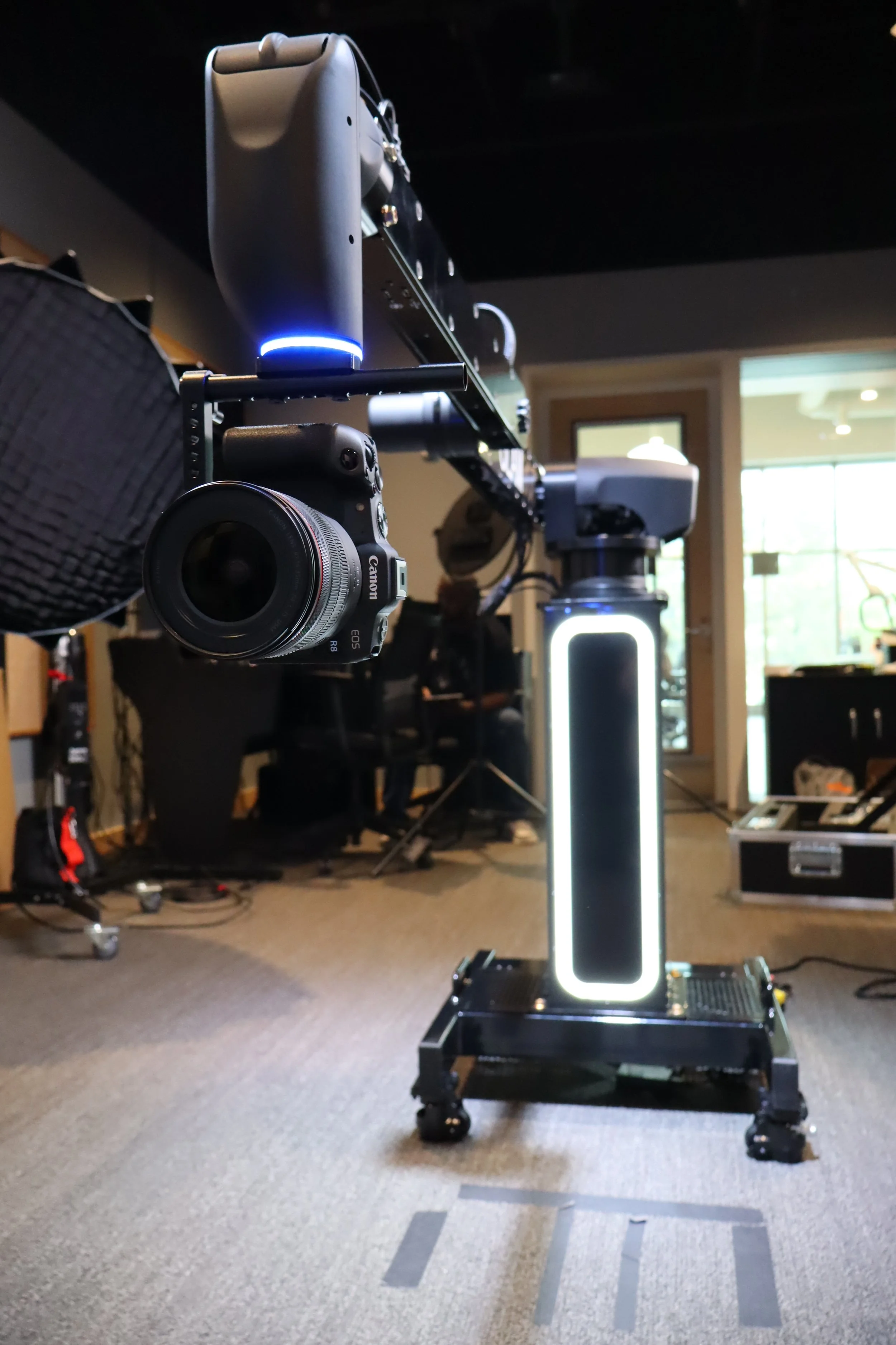 An event Glambot mounted on a specialized rig in a room with artificial lighting, various equipment, and a large window in the background.