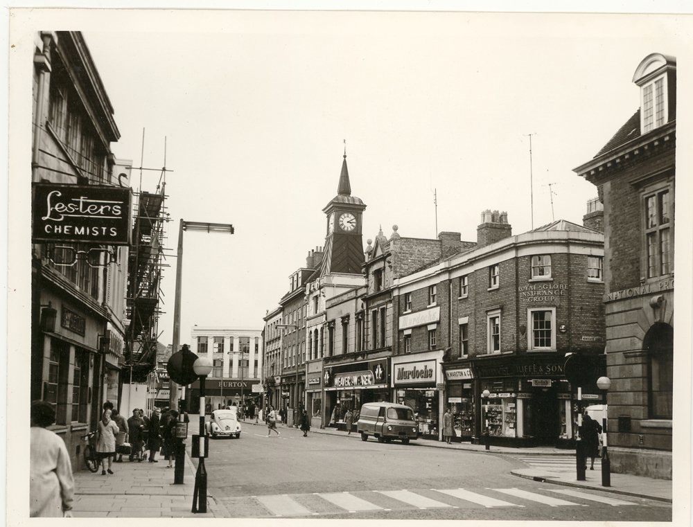 Nuneaton in 1962. Although the shops have changed, the buildings are virtually the same. Weaver to Wearer is now Vodaphone, Iliffes was O2 (now empty), Burtons at the bottom of Market Place is Clintons, Lesters Chemists is Boots.  Pedestrianisation w