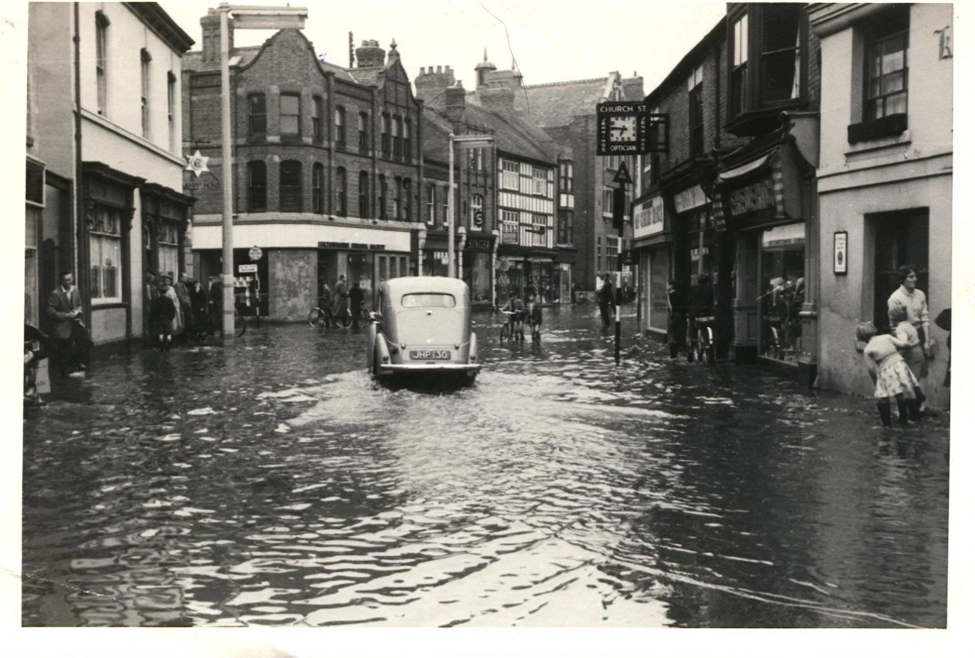 Church Street in the floods. 1950's. The white building on the left is the Saracens Head that stood on the corner of Bridge Street. The car was registered in August 1949 (according to the number plate) so the photo is early 50's.  Floods were common 