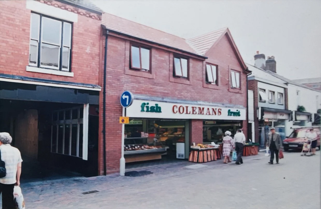 Stratford Street after the demolition of the Royal Picture House. To the left is the garage of Smiths Undertakers, next to it is Colemans Fish and Fruit, a long established local business. The 'Fruit' section of Colemans used to be 'Scoop and Save', 