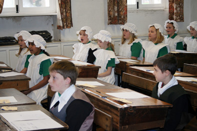 class of school children answering teacher's questions in victorian re-enactment