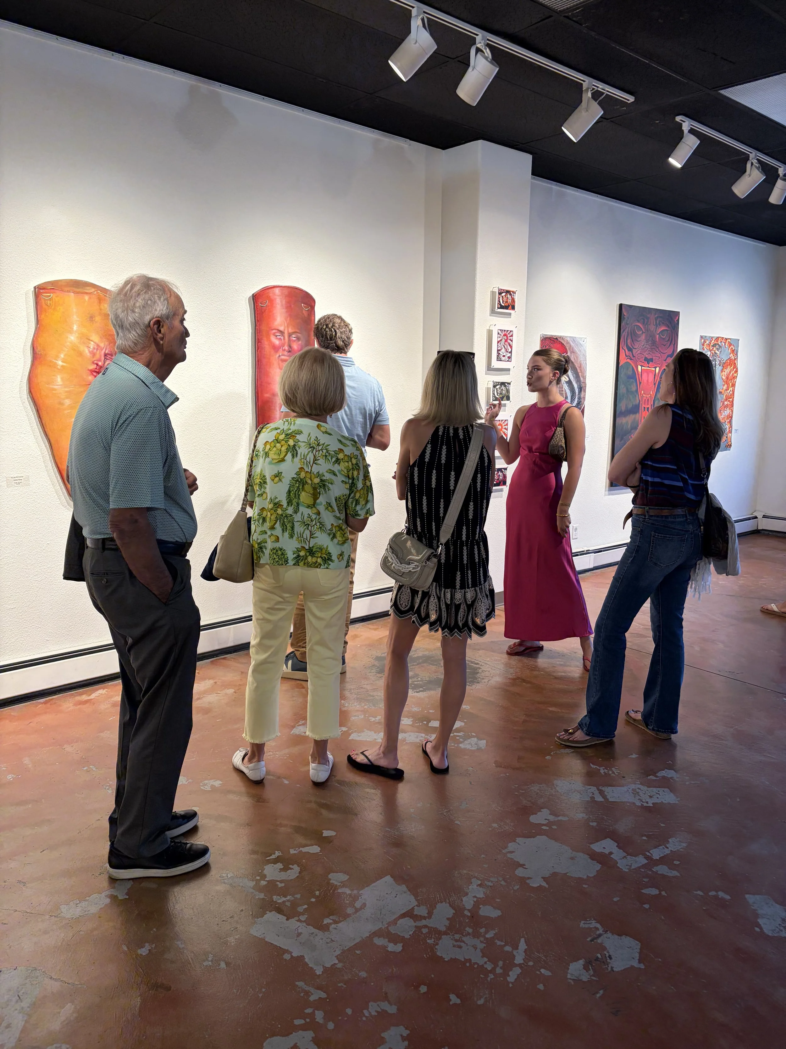 Artist explaining work to group of people inside a gallery with white walls.