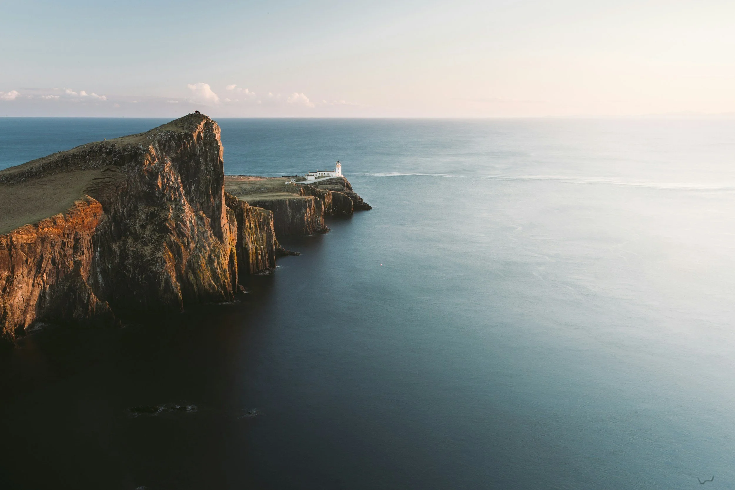 Cliffs and a lighthouse on a coastline with the ocean and sky in the background.