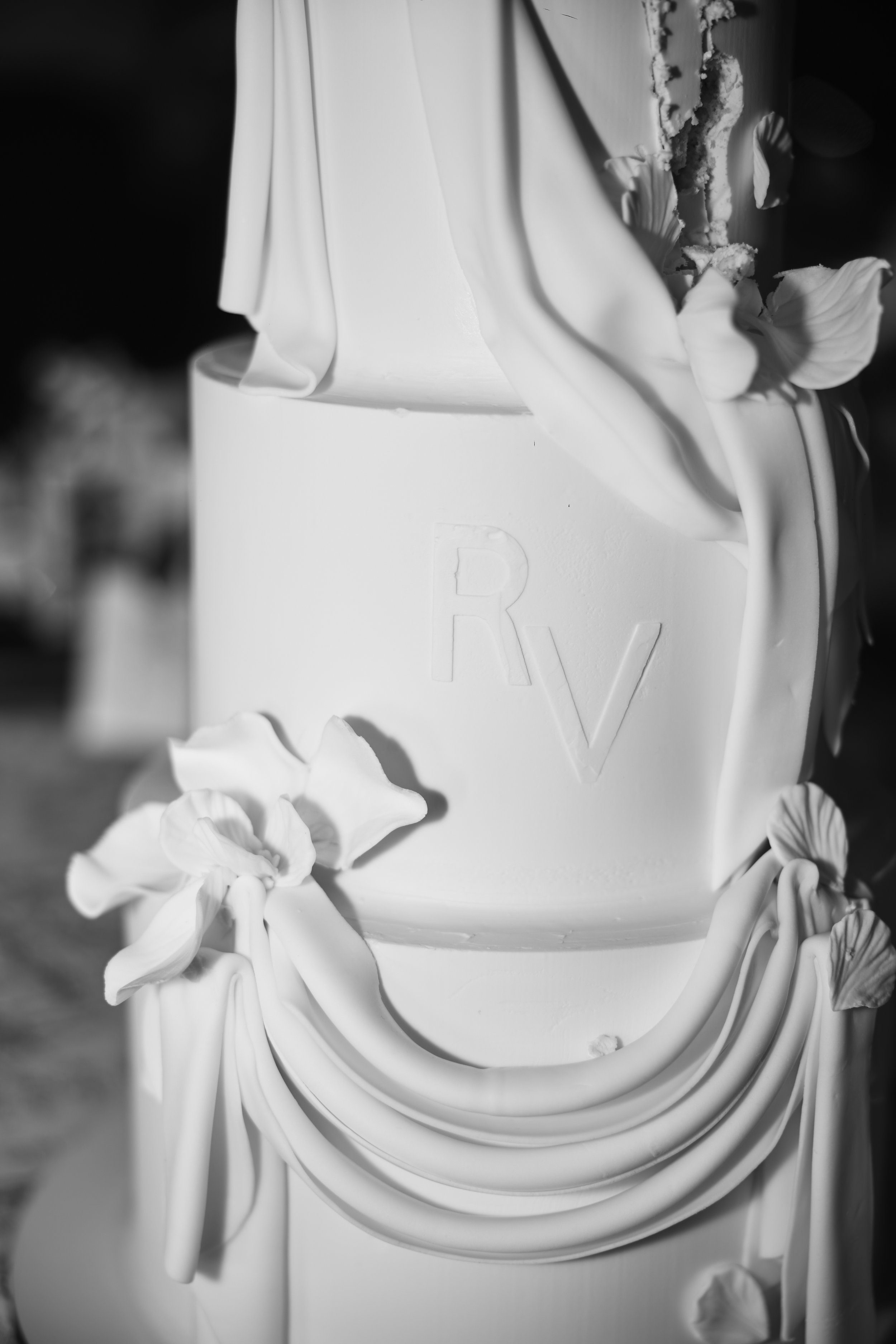 Pastel de boda decorado con flores blancas y detalles en relieve en la superficie, en color blanco.