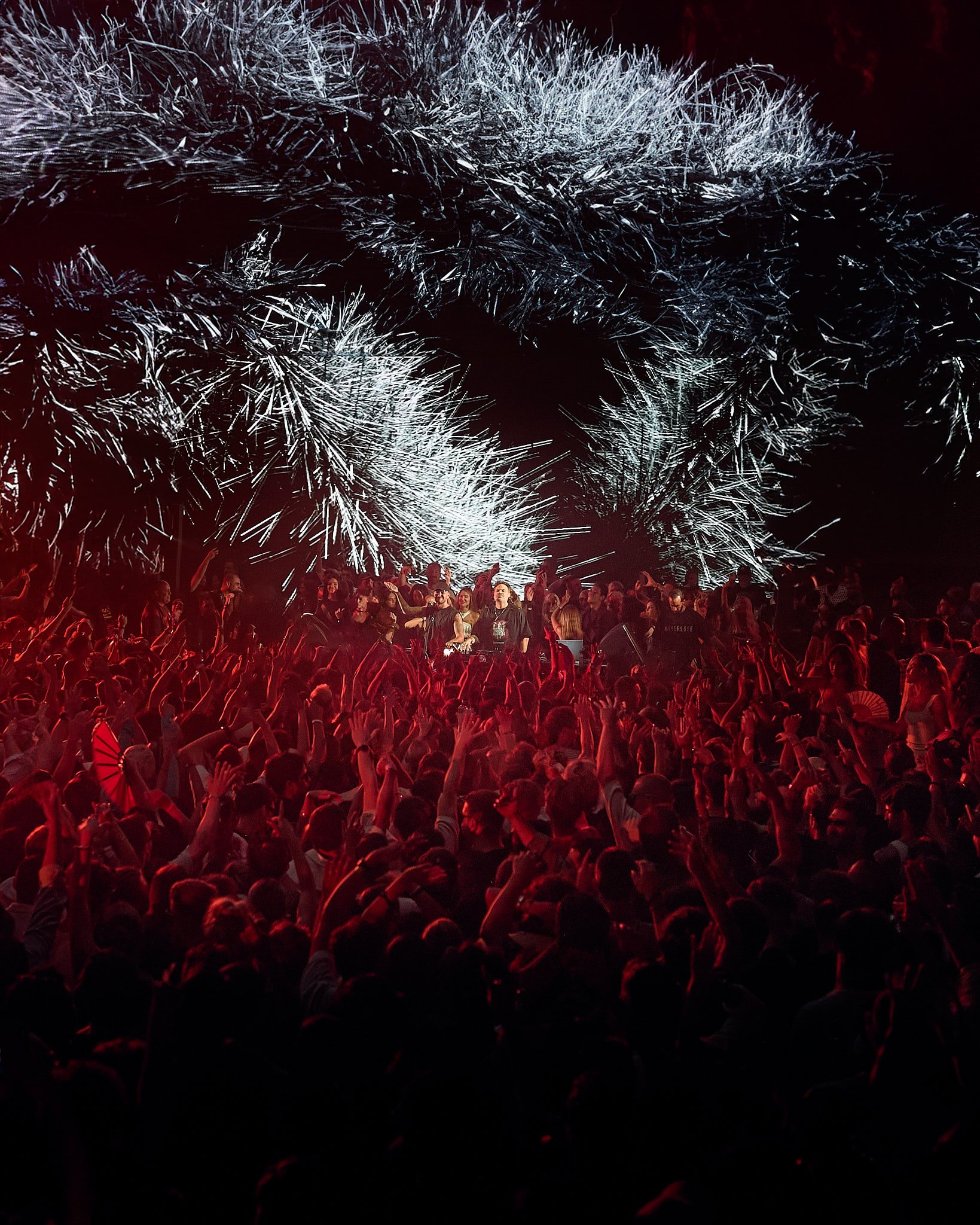 Una multitud de personas en un concierto con un escenario con pantallas que muestran efectos visuales.