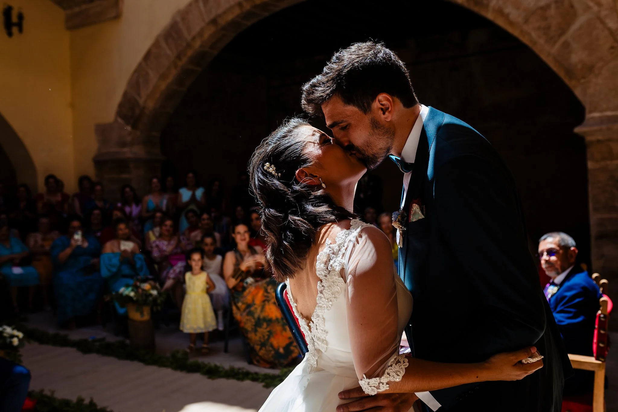 Mujer con vestido de novia en un baile en un evento elegante, rodeada de personas sentadas en mesas, con techo decorado con luces pequeñas.
