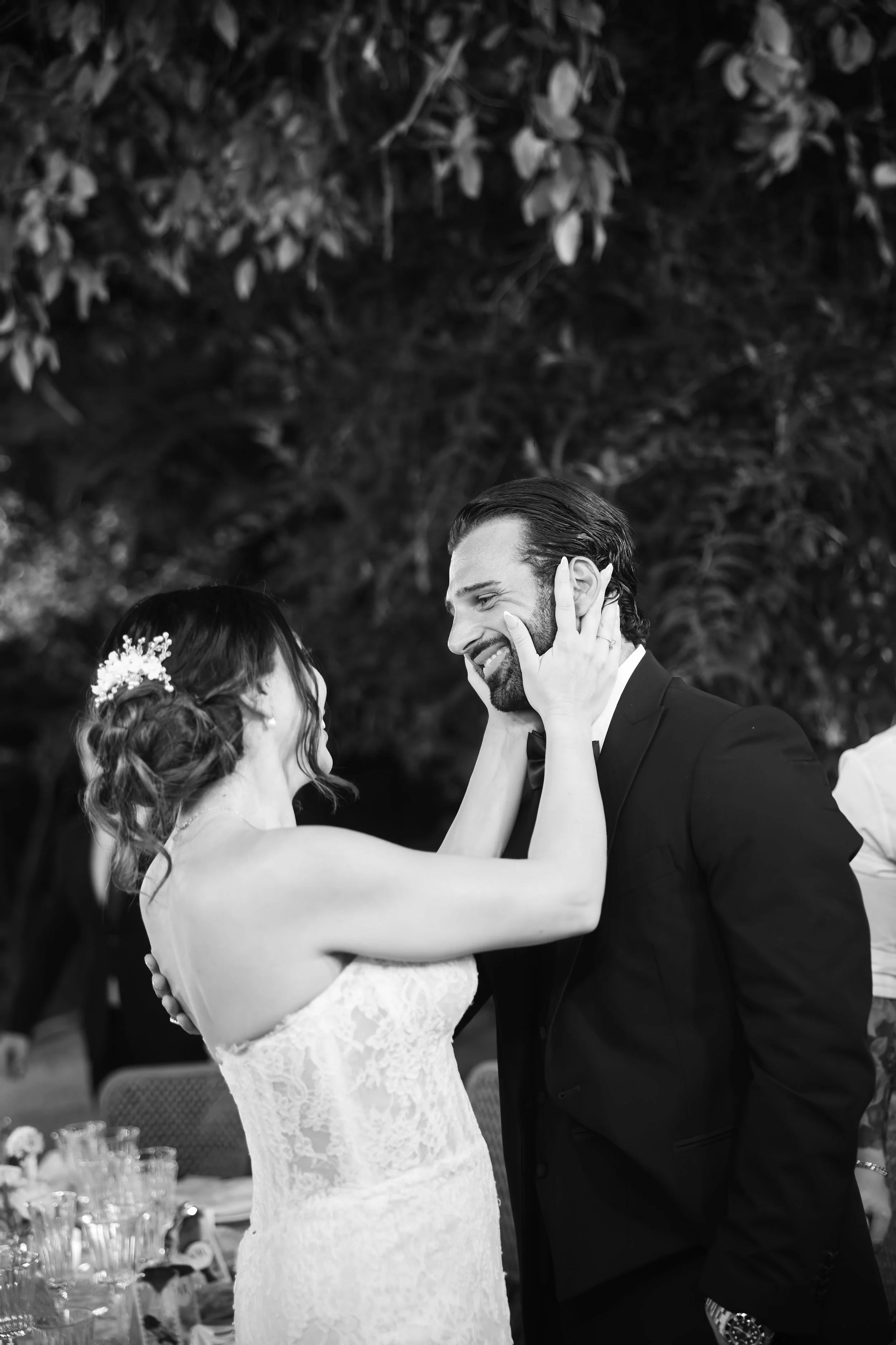 Pareja de recién casados bailando en una ceremonia de matrimonio, ella en vestido de novia y él en traje, con fondo de árboles y ramas.