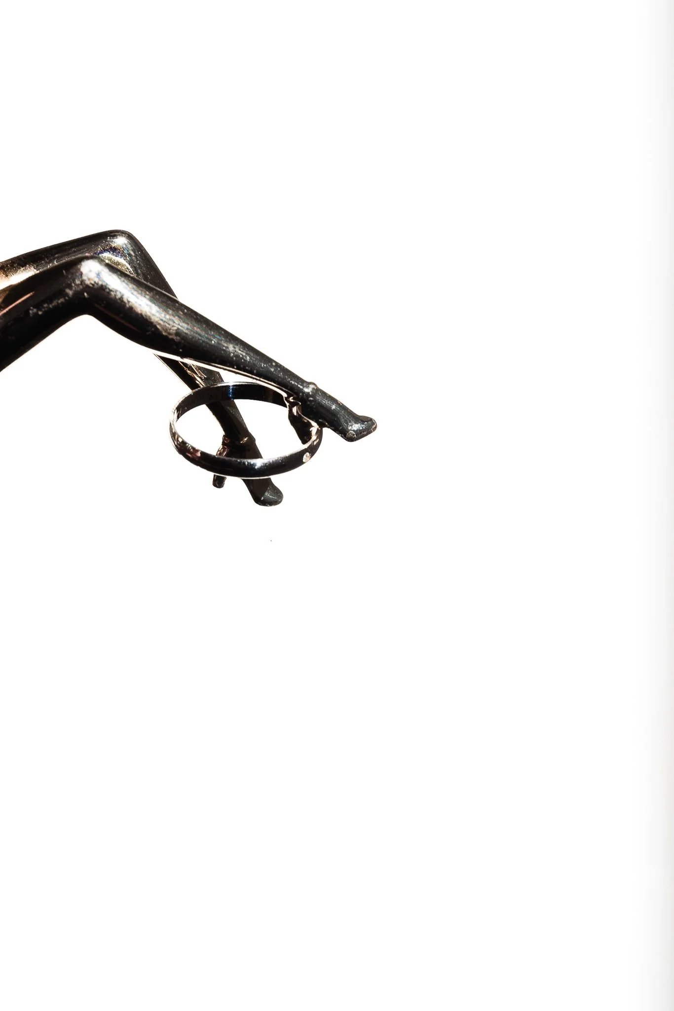 Instrumento de cirujía en metal, con un anillo de agarre, en un fondo blanco.