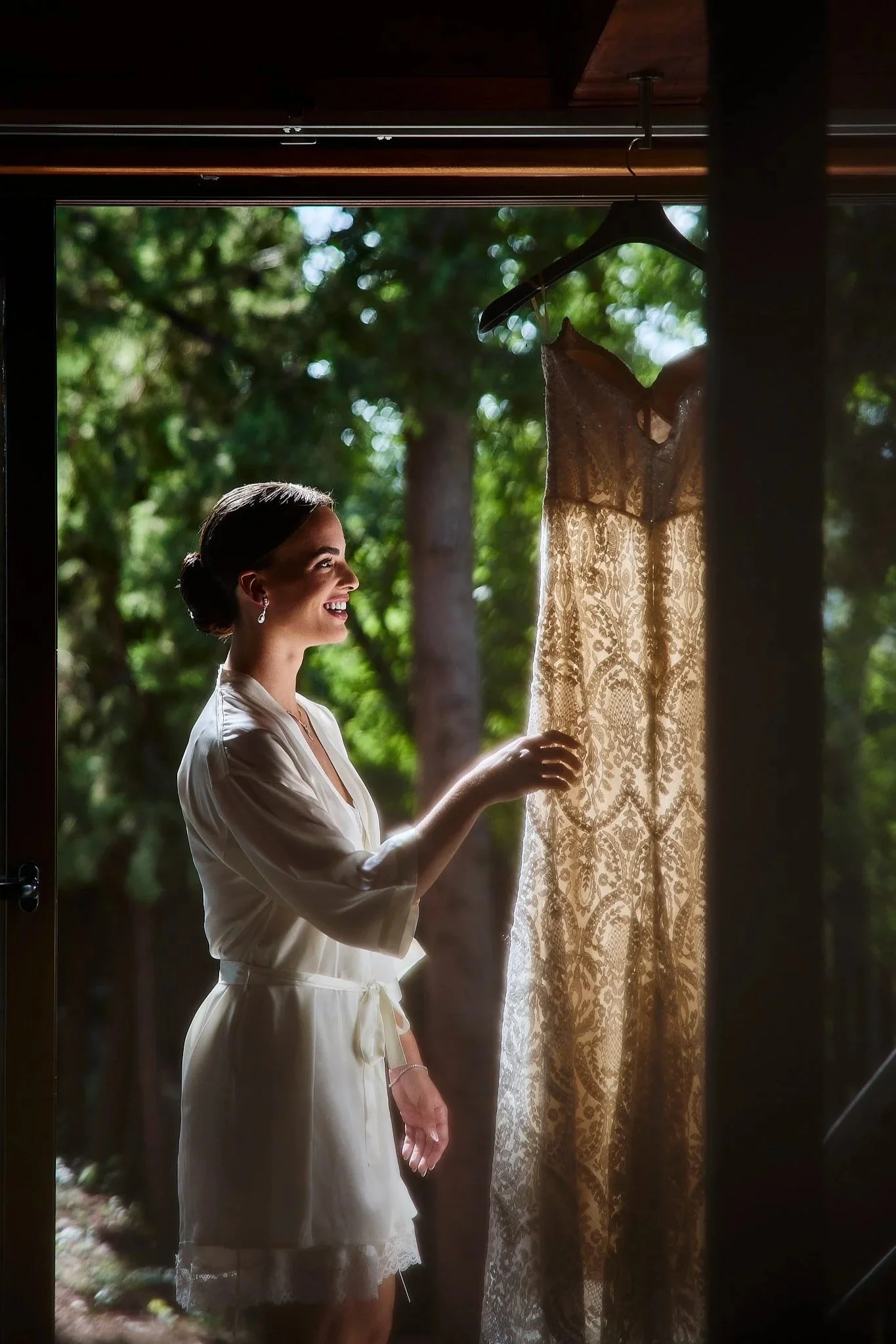 Novia en Valencia mirando su vestido de novia con luz de contraluz cinematográfica. Estilo documental y artístico. Fotografía atemporal.