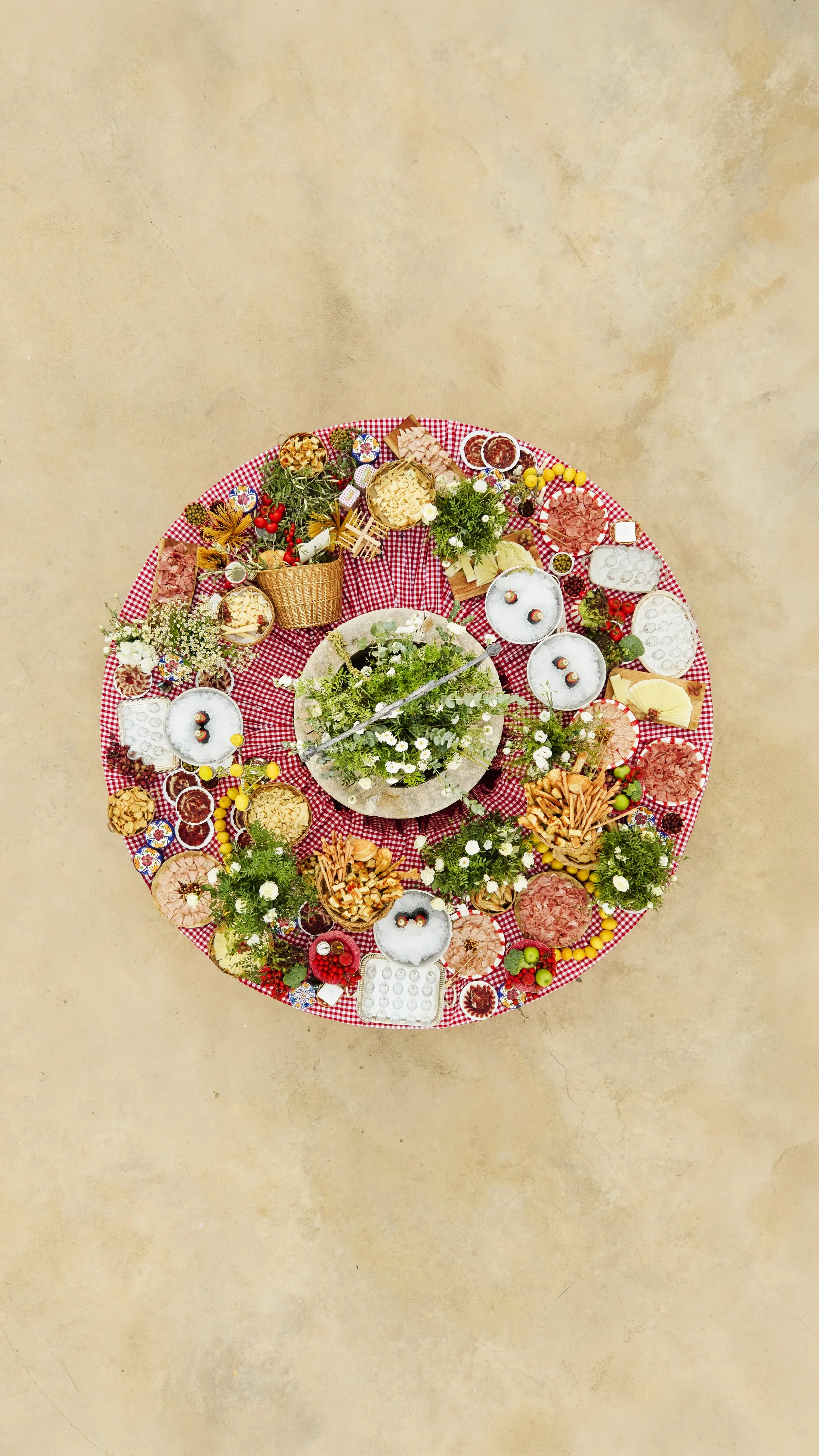 Mesa redonda con comida variada y decoraciones florales, vista desde arriba, en un ambiente de colores brillantes y campestres.