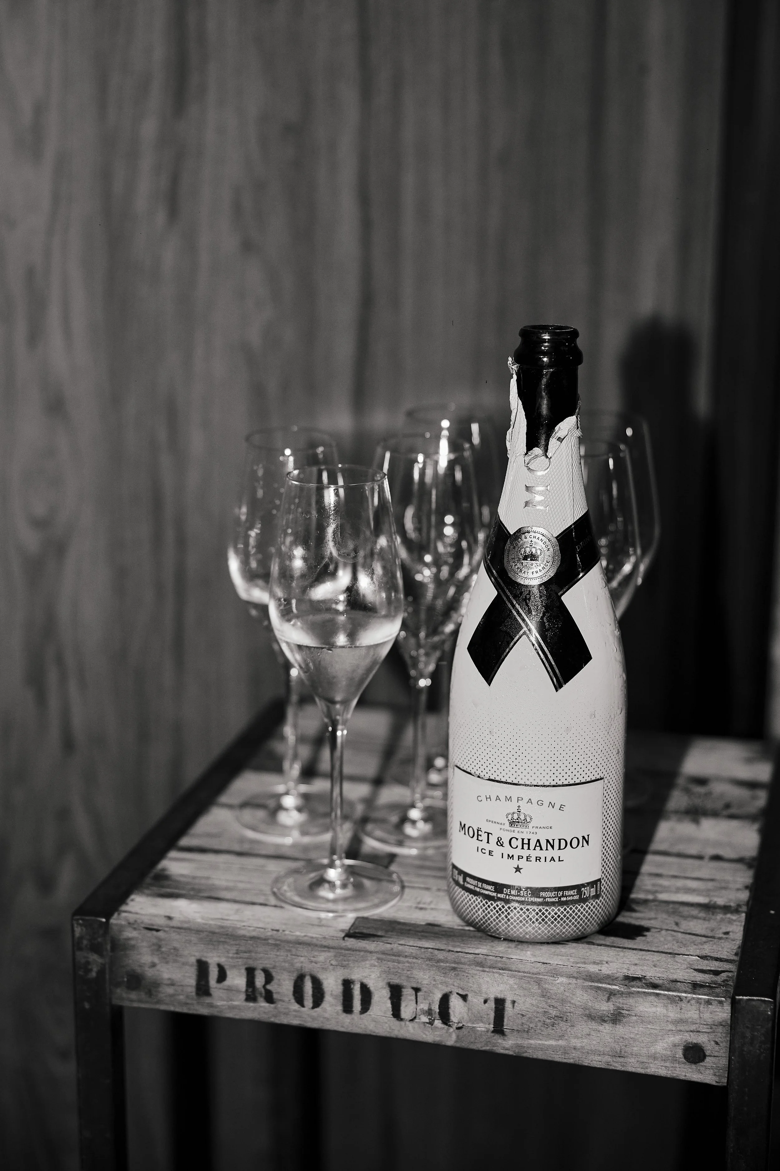 Botella de champagne Moet & Chandon Ice Imperial y varias copas en una mesa de madera con la palabra 'PRODUCT'.