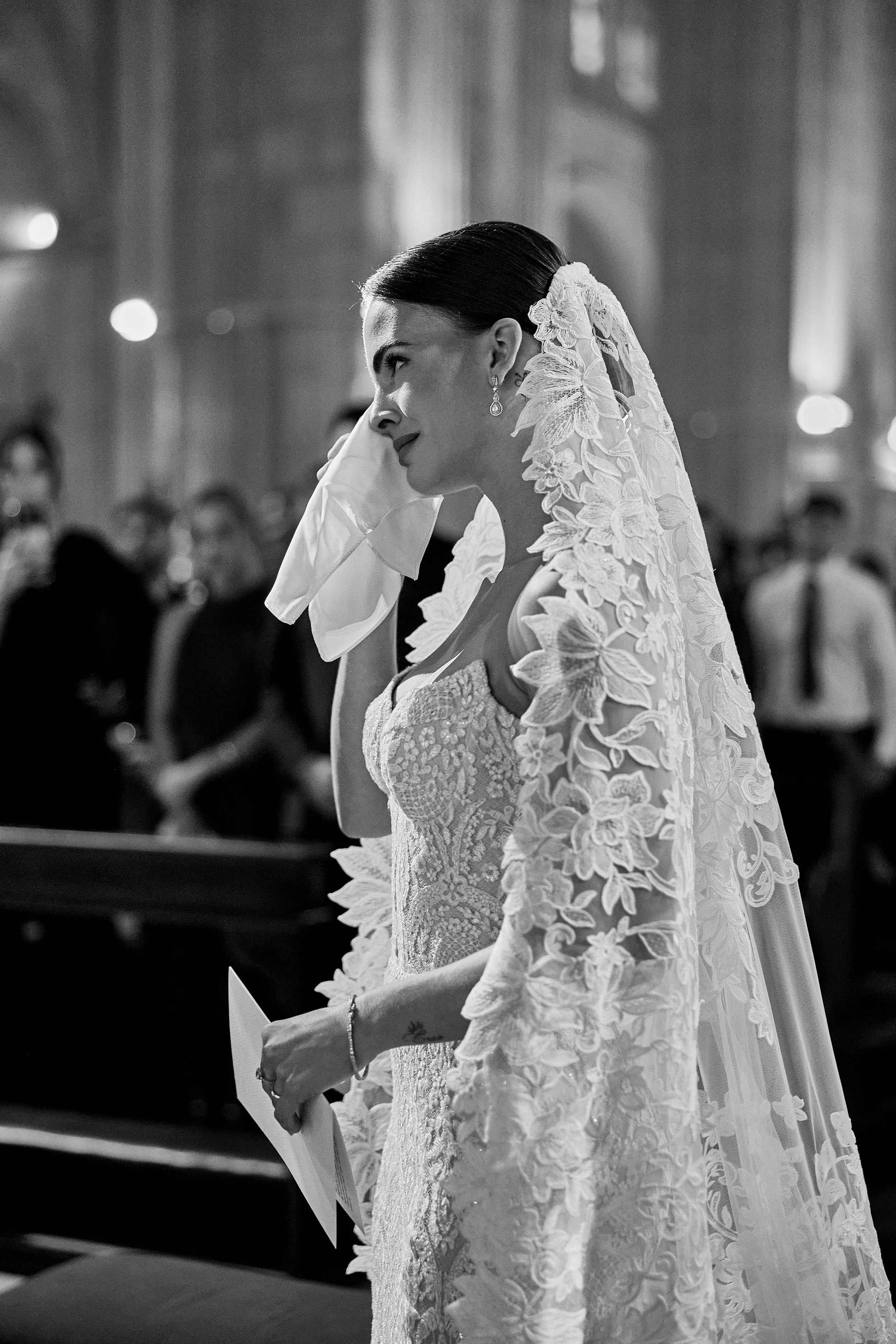 Mujer con vestido de novia y velo en una iglesia, llorando quizás en un momento emotivo de su boda.