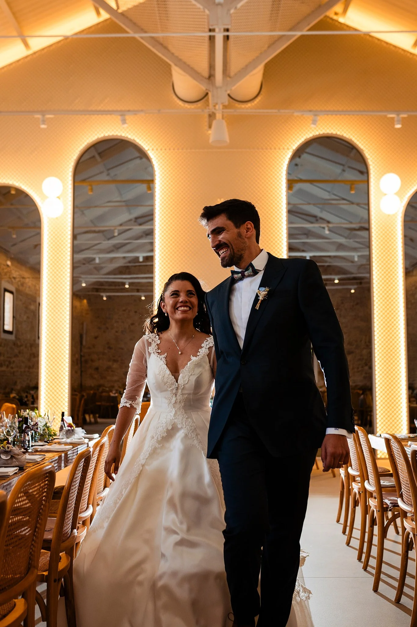 Pareja de recién casados en un salón de bodas decorado con luces cálidas.