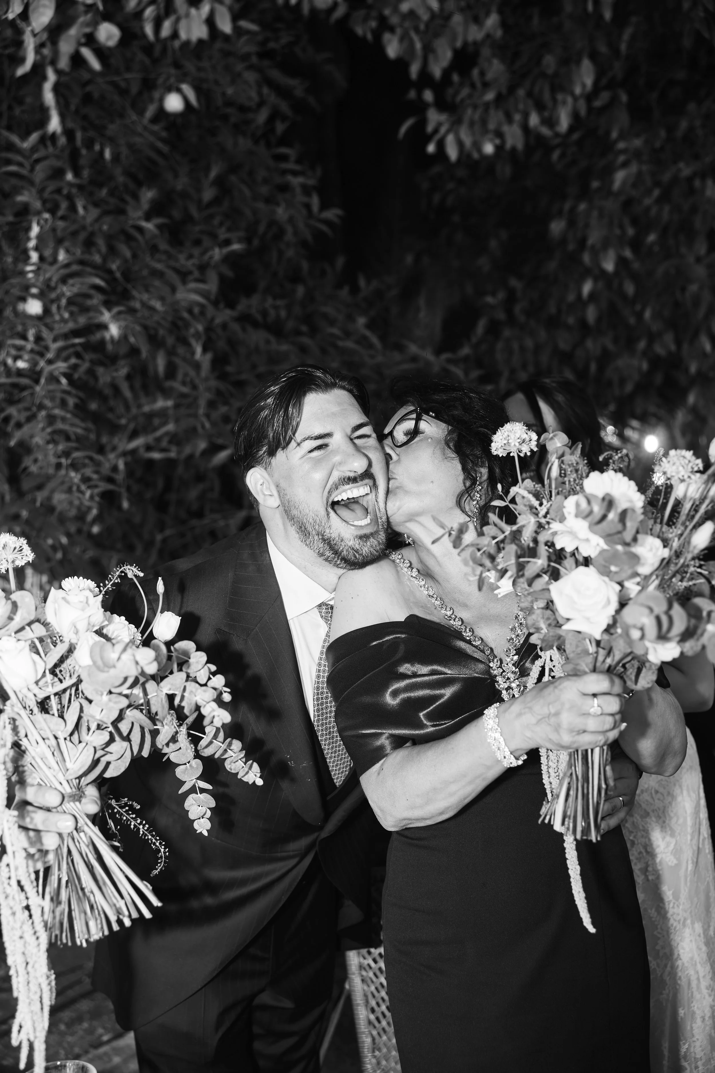Una pareja en una boda, la mujer con vestido y el hombre con traje, compartiendo un momento de alegría y cariño, rodeados de arreglos florales y detalles decorativos.