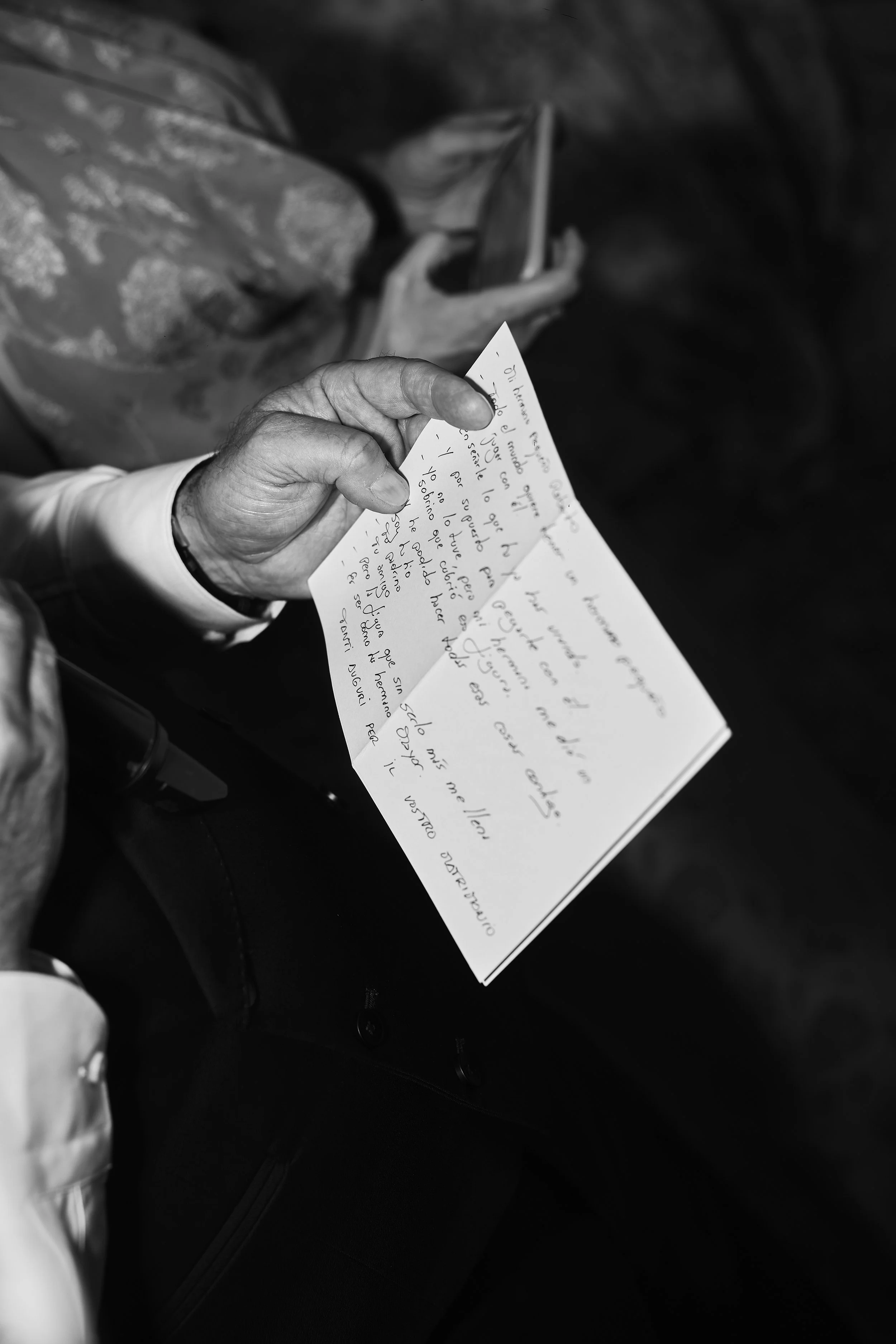 Mano sosteniendo una carta escrita a mano, vista en blanco y negro.