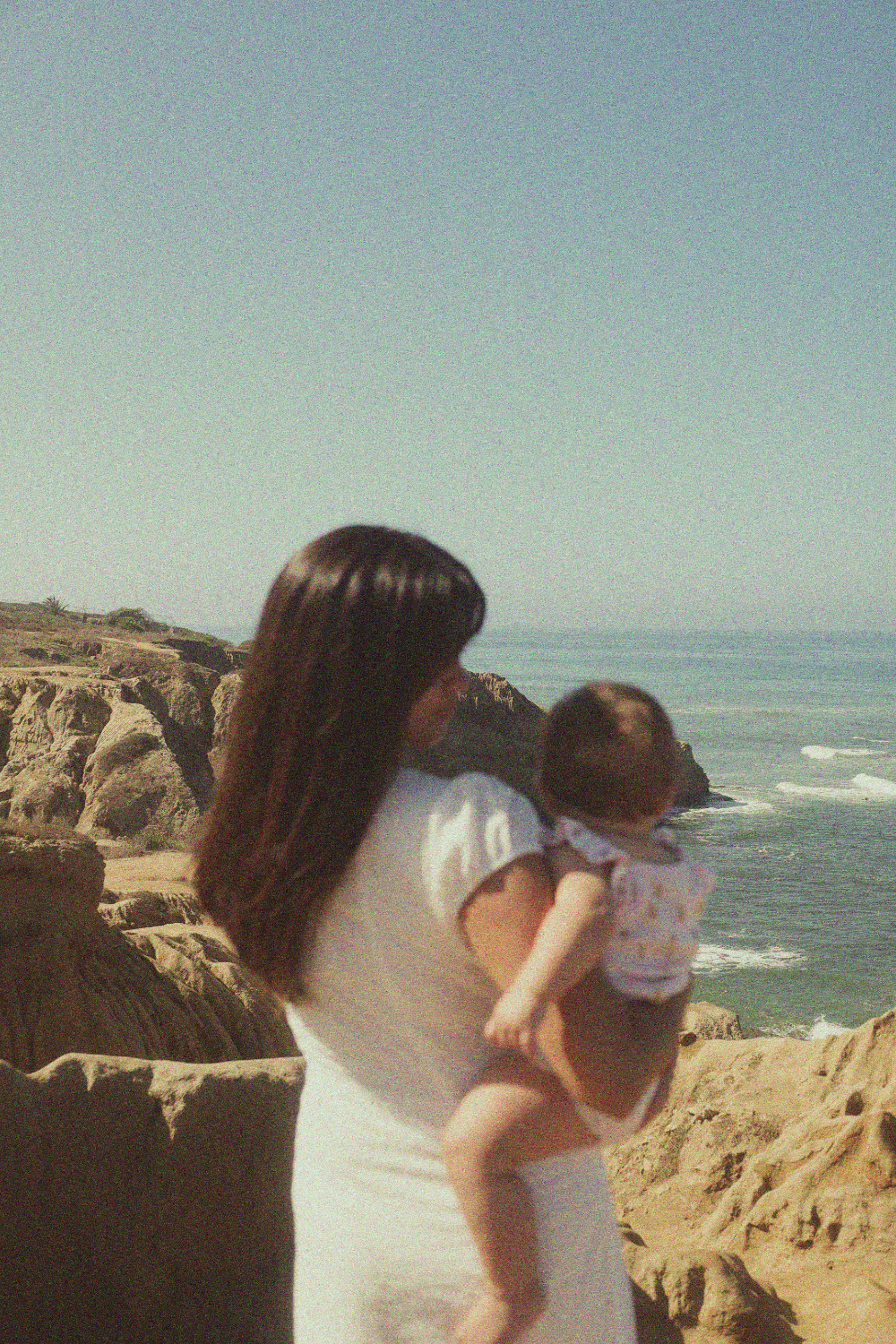 Mother holding a child on a rocky beach in San Diego.