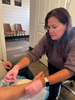 A woman taking a person's blood sample in a medical setting.