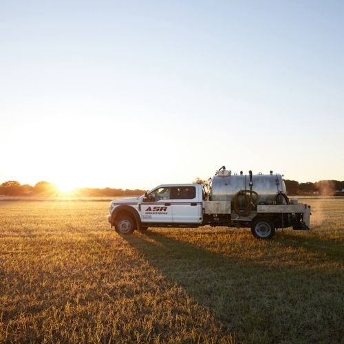 Aspen Site Rentals service truck with a pump tank in a field at sunset