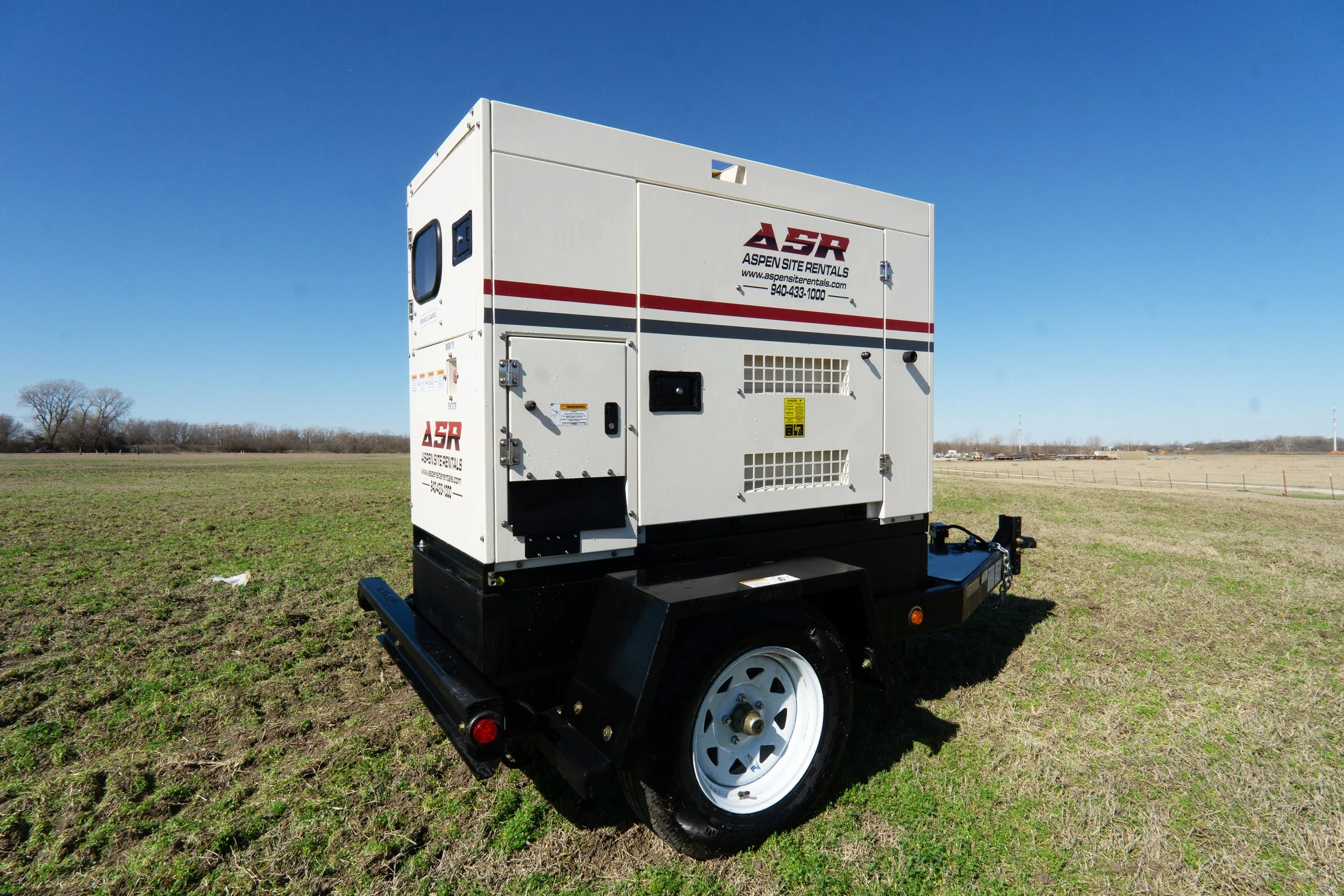 25 kW towable diesel generator with a red stripe in a green field