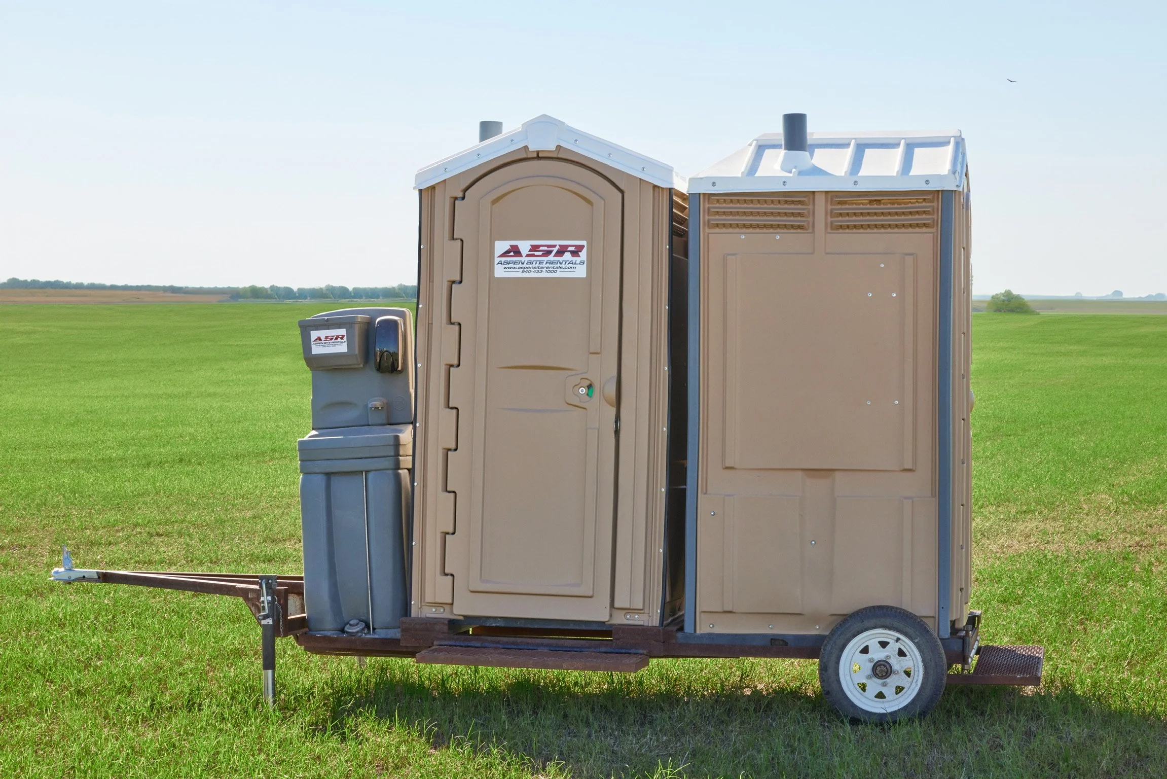 Two portable toilets on a small trailer with a hand-wash sink station attached at one end