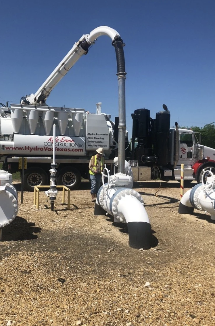 Vacuum excavation truck boom over buried pipe work with a crew member in hi-vis