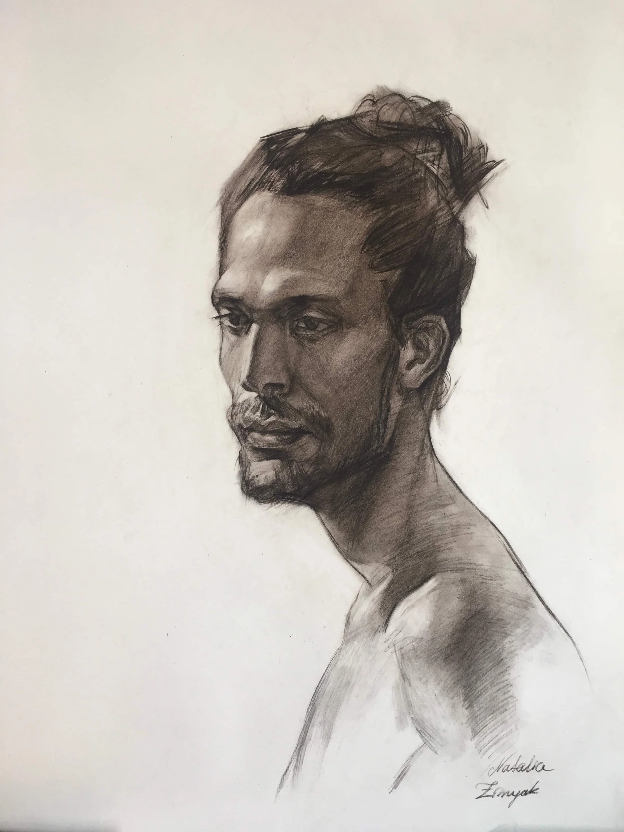 A pencil sketch of a young man's portrait with short, wavy hair and a beard. The man is looking slightly to the left with a serious expression. The artist's signature, 'Natalka Emyak,' is visible at the bottom right.