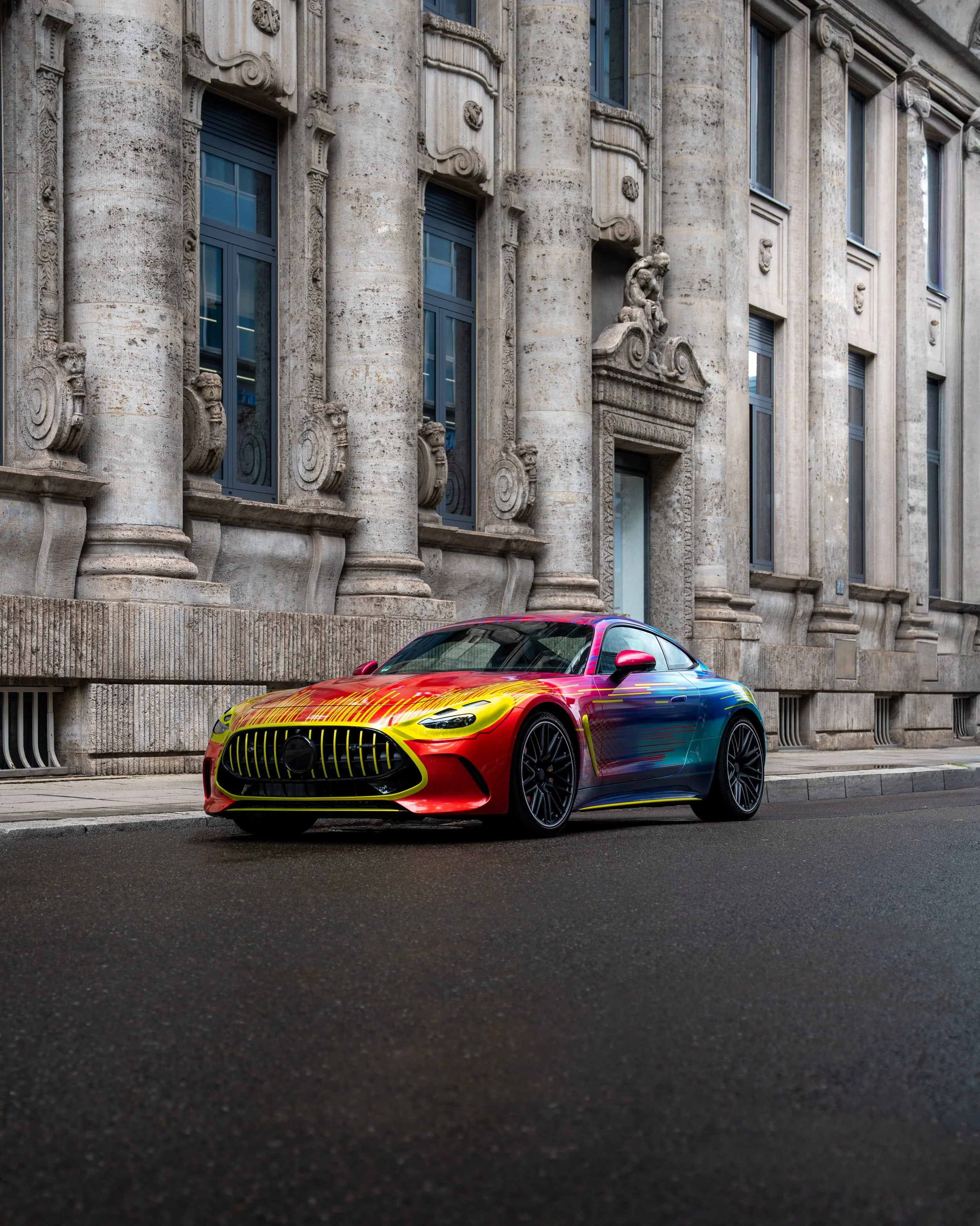 Ein bunt lackiertes Auto, das vor einem alten, steinernen Stadthaus parkt.
