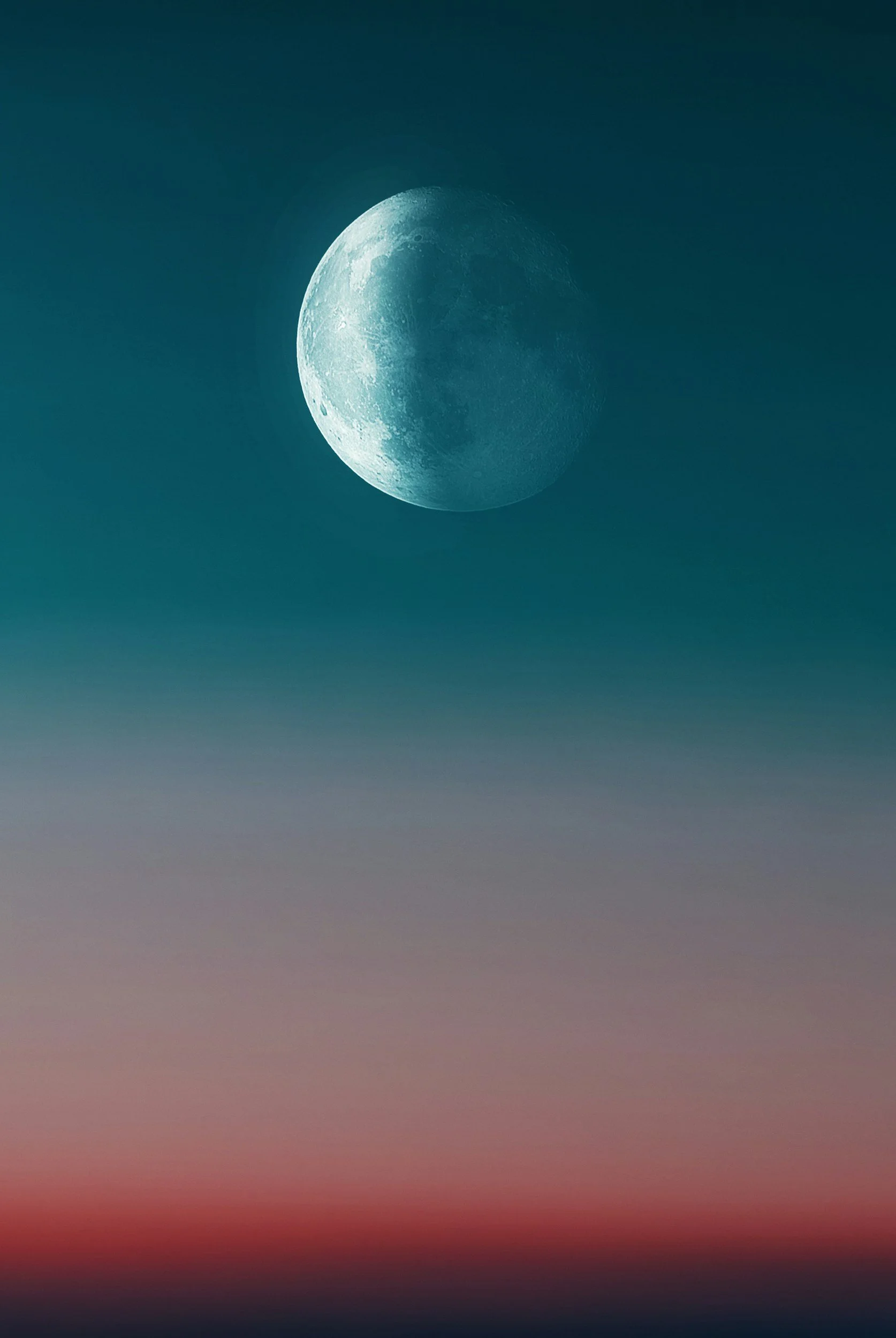 Image of a waxing moon during dusk, with a gradient sky transitioning from deep blue to reddish hues near the horizon.