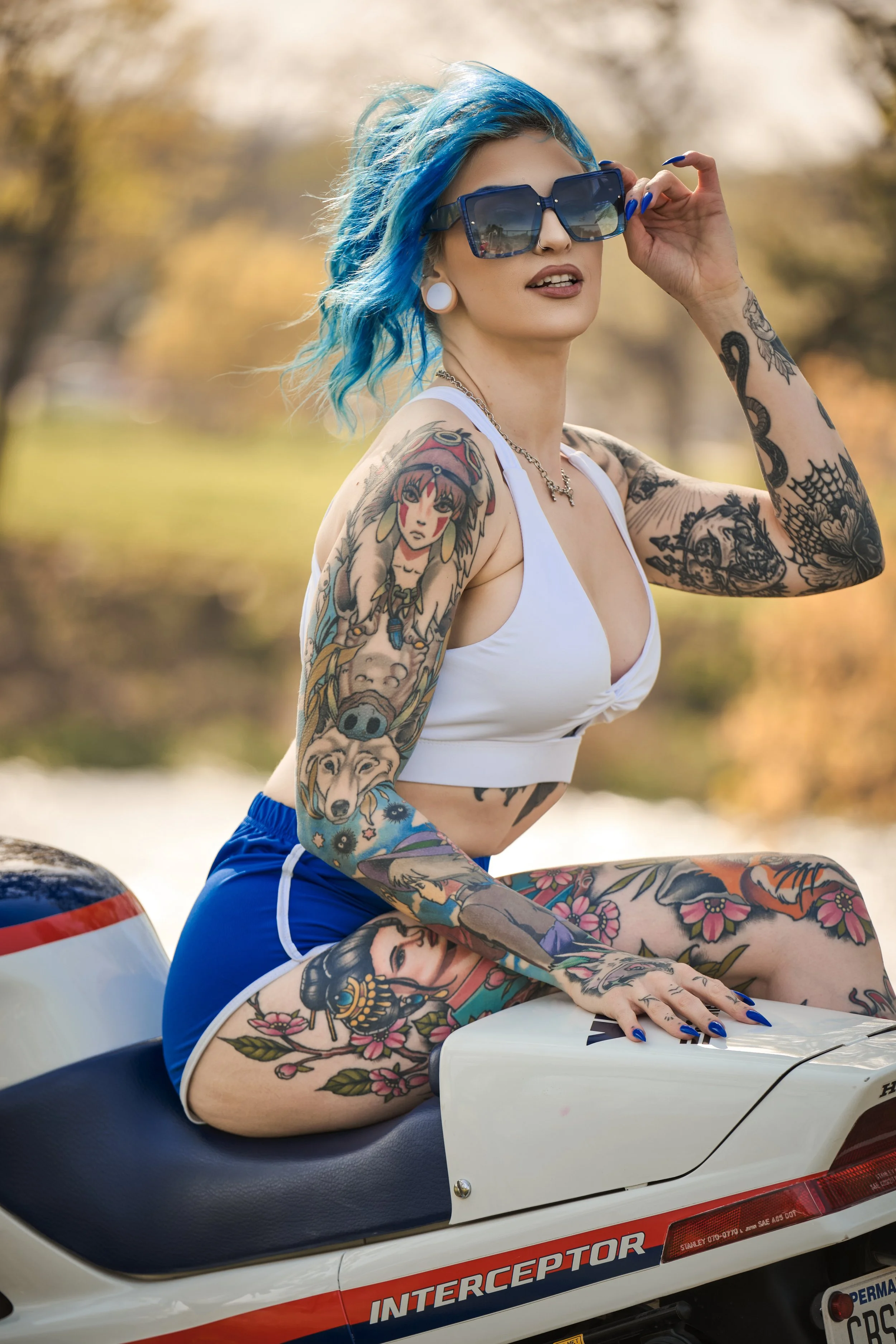 Whitley sitting on a white Honda motorcycle with red and black accents, outdoors with blurred trees in the background.