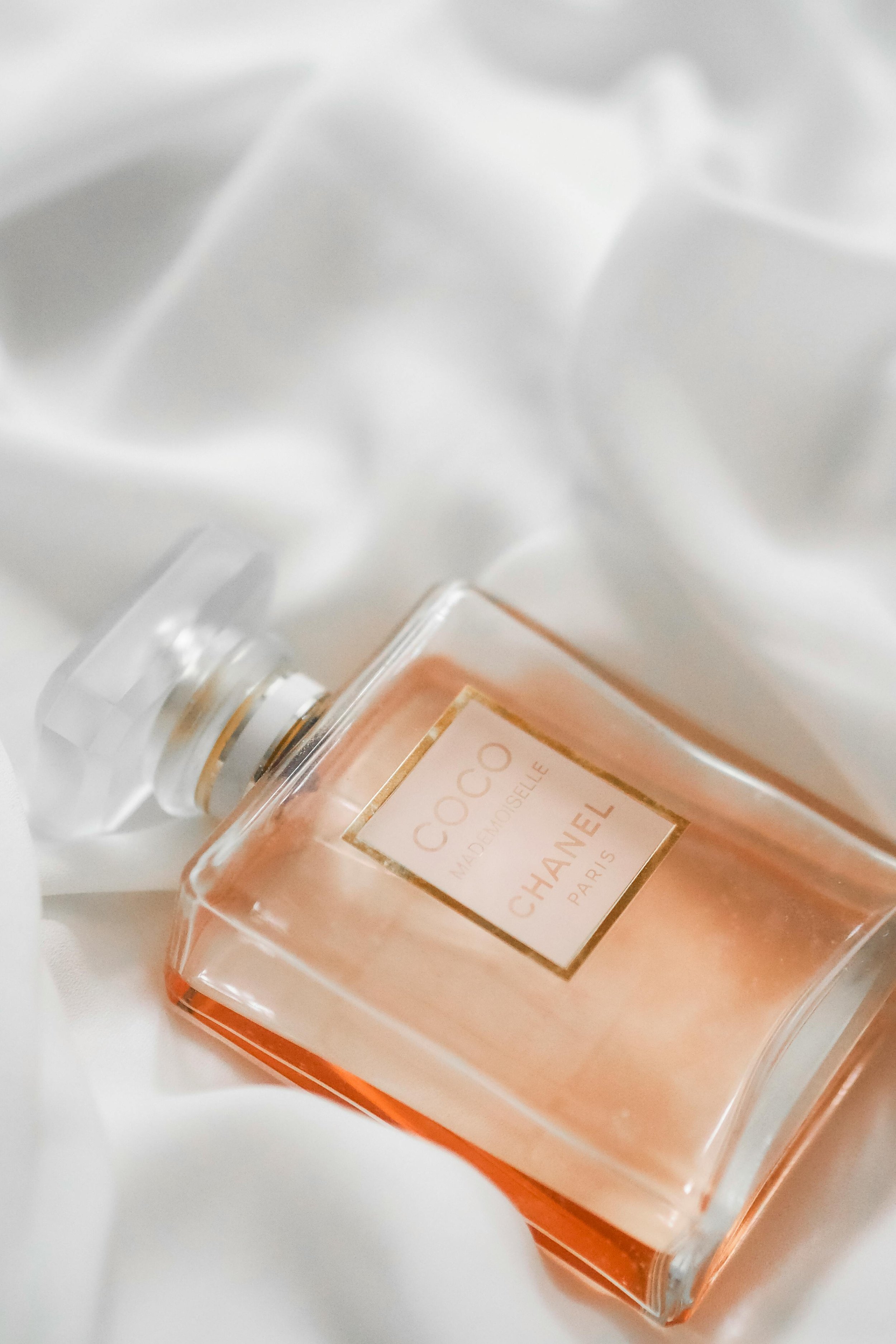 A bottle of Chanel Coco Mademoiselle perfume lying on a white fabric background.