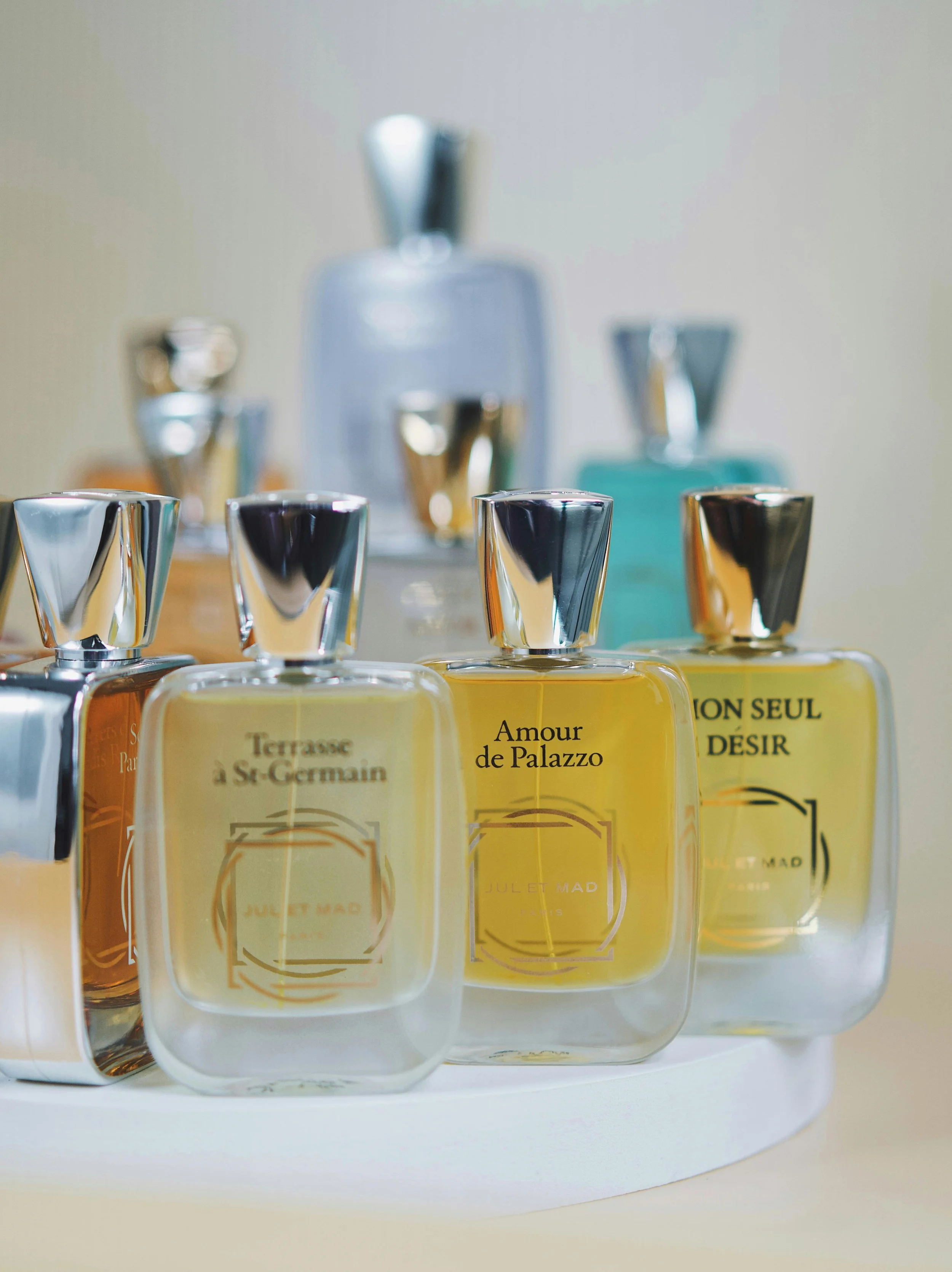 A collection of colorful perfume bottles with silver caps on a white surface, some with visible labels in French.