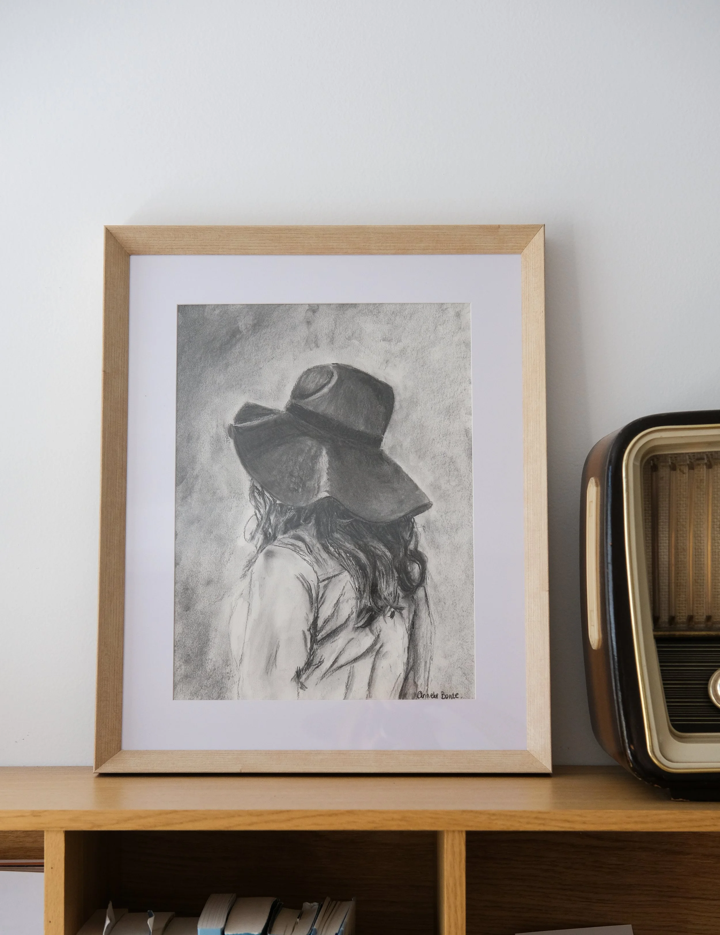 Tekening van een vrouw met een grote hoed en lange haar, getekend in houtskool.