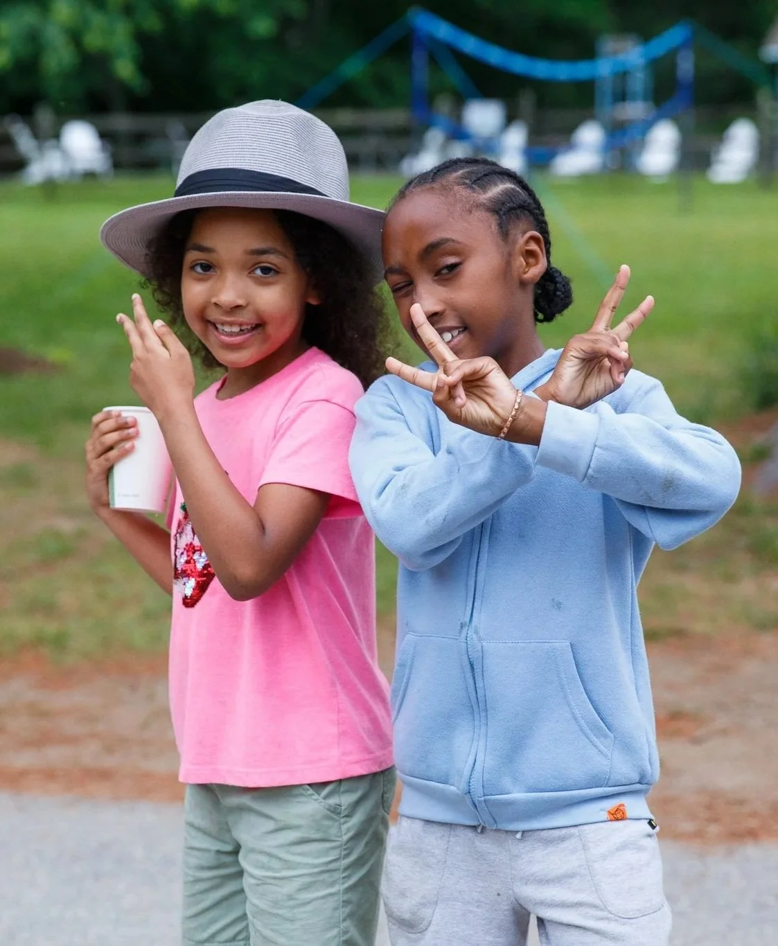 Two young kids pose for the camera making peace signs with their hands