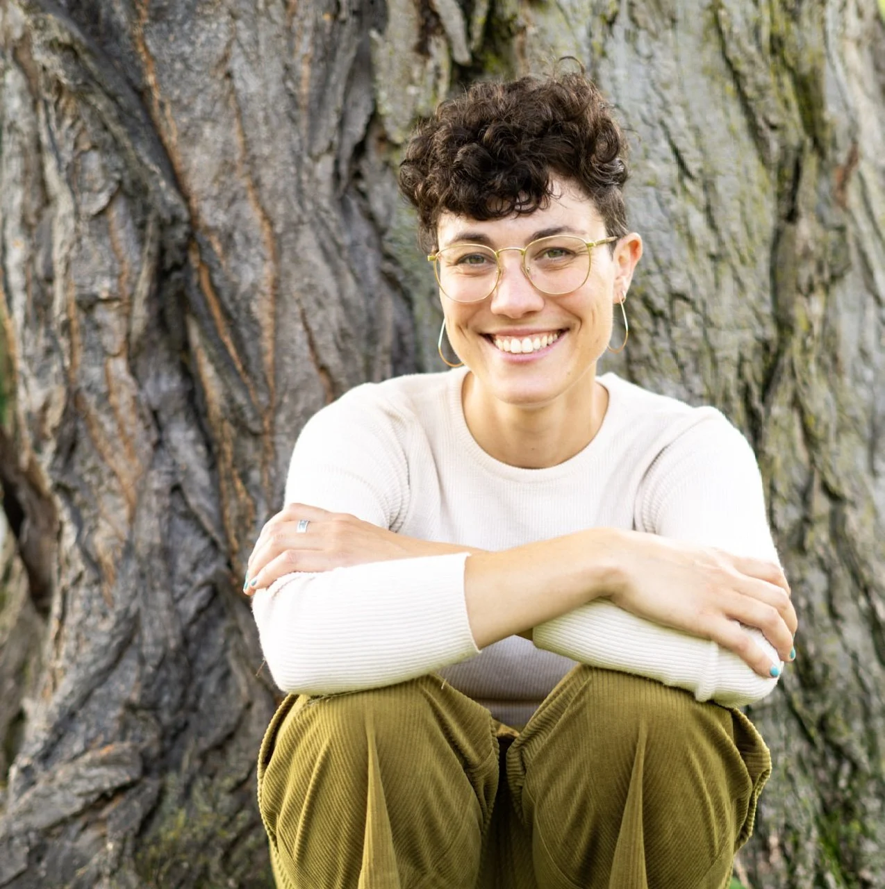 A headshot of Molly Bajgot sitting against a tree