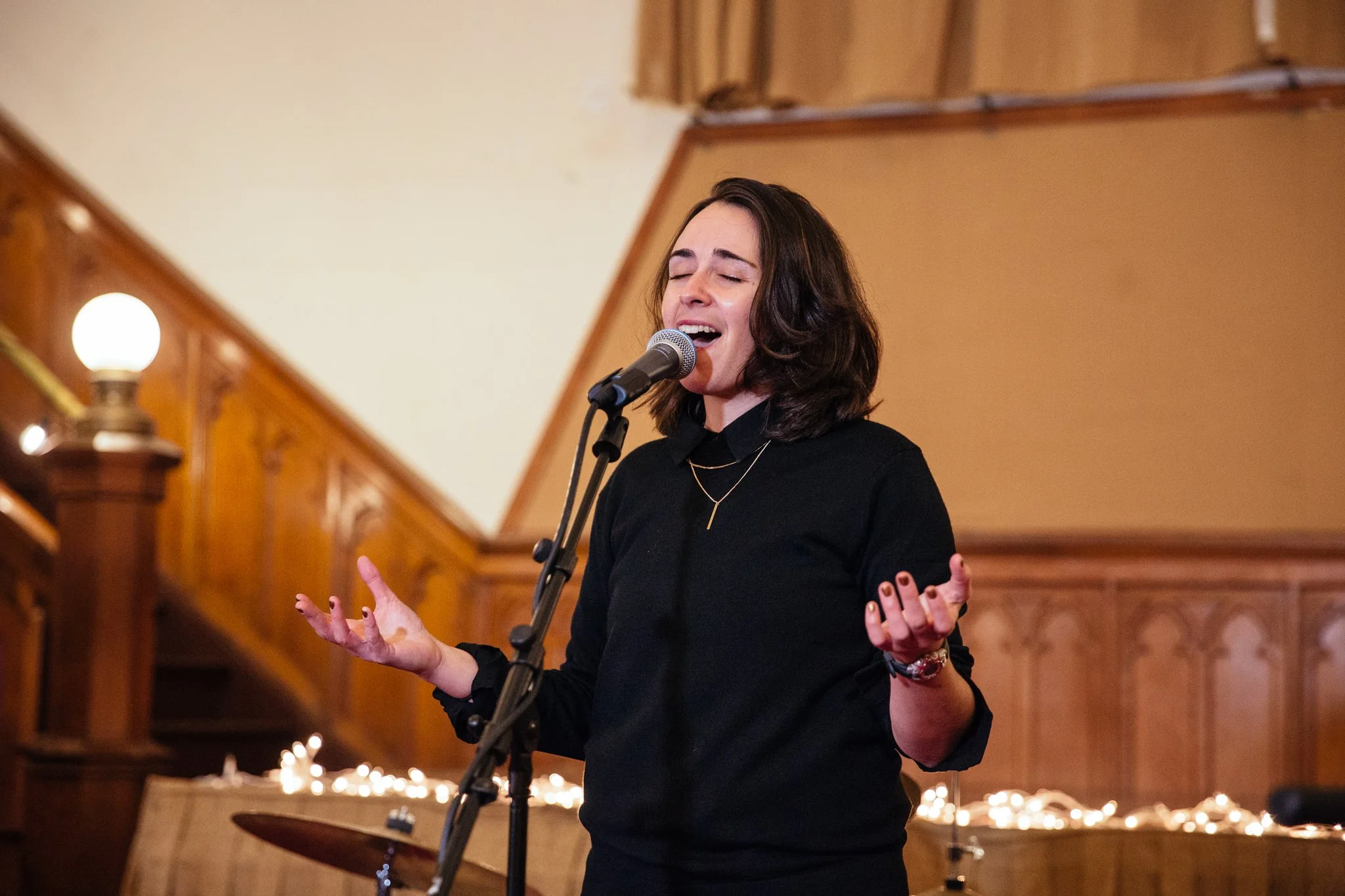 A headshot of Aly Halpert singing into a microphone at a concert
