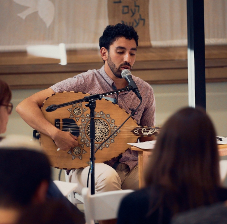 A photo of Yoni singing and playing the oud